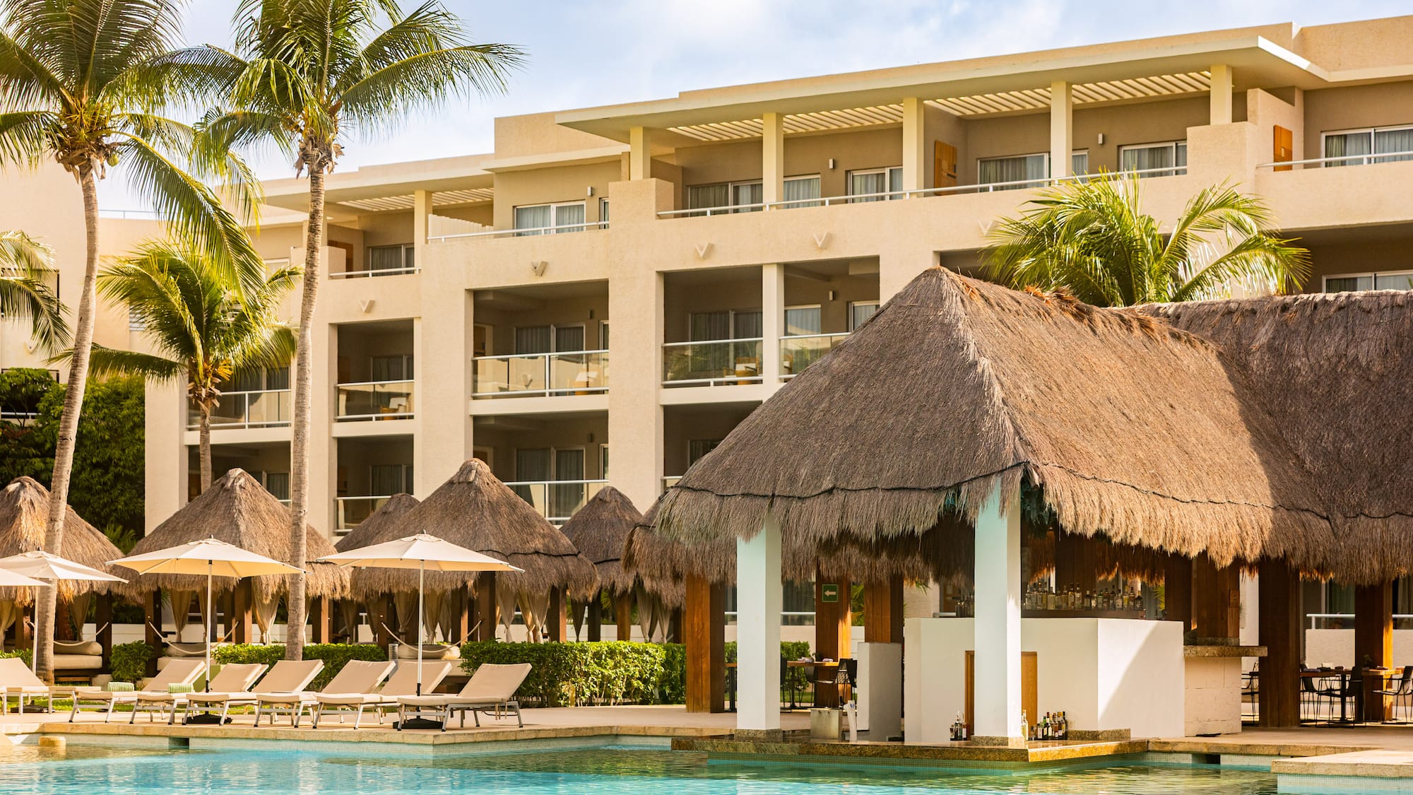 Tropical resort hotel with swimming pool, palm trees, and swim-up bar.
