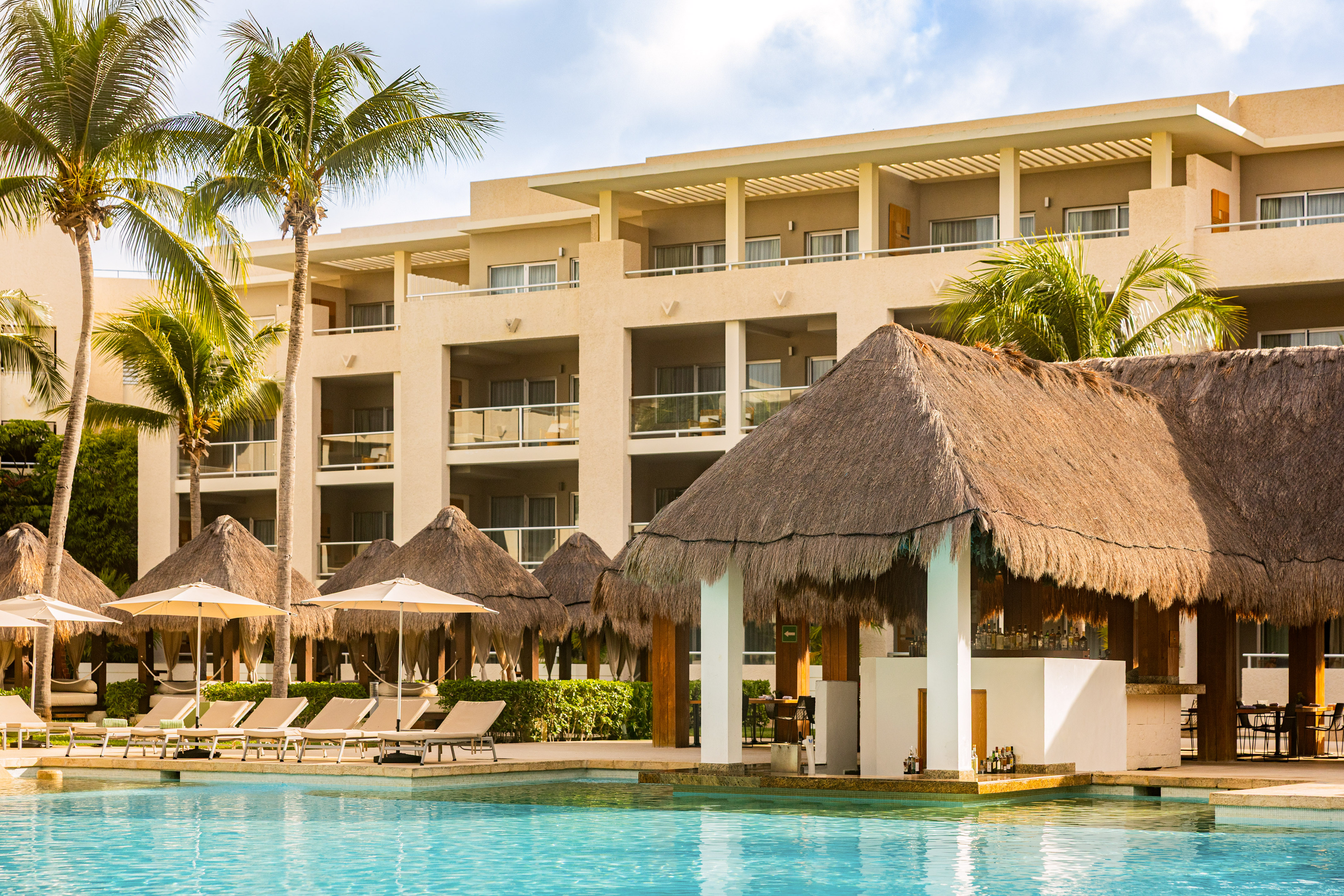 Tropical resort hotel with swimming pool, palm trees, and swim-up bar.