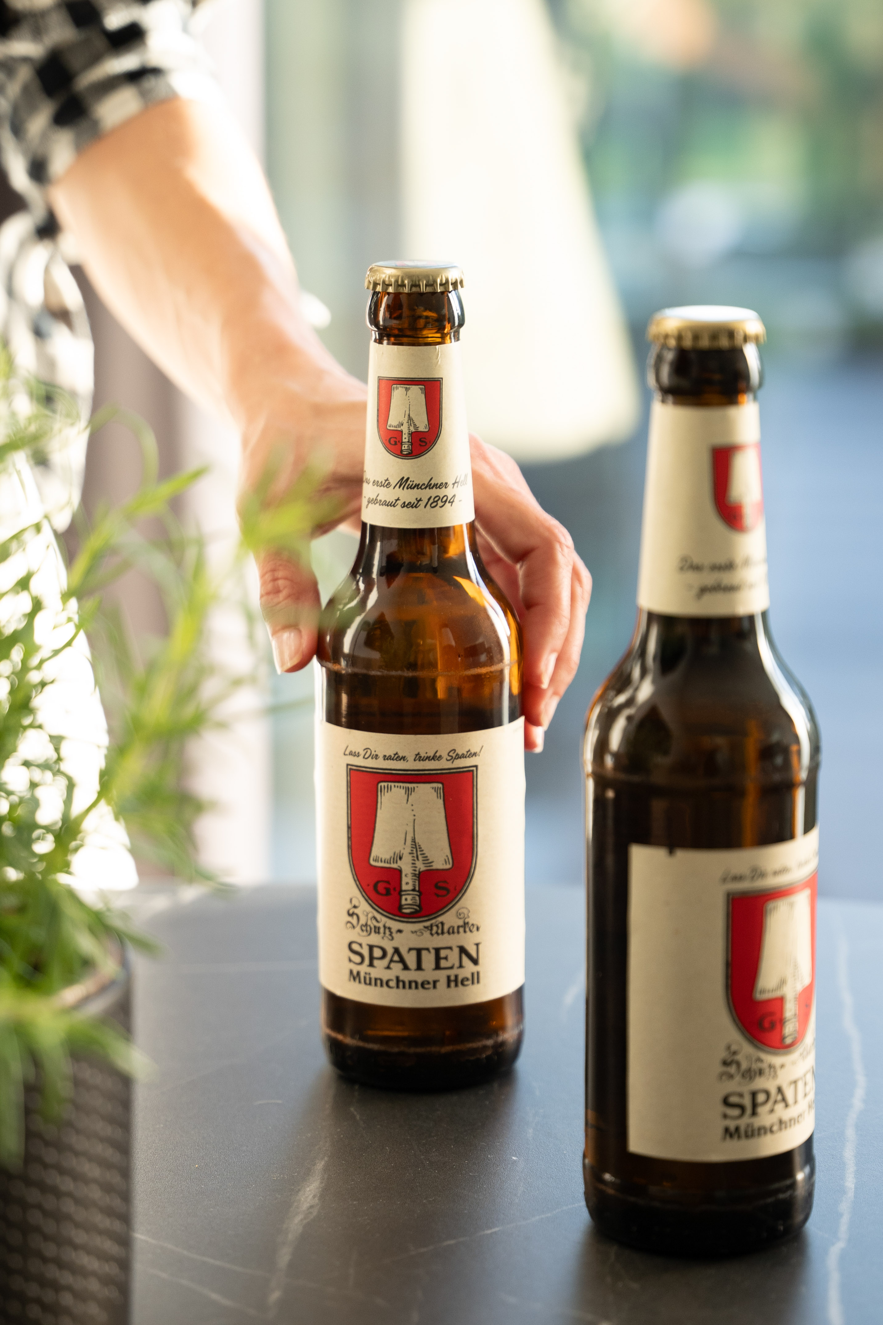 Botellas de cerveza Spaten Münchner Hell, una sostenida por una mano.