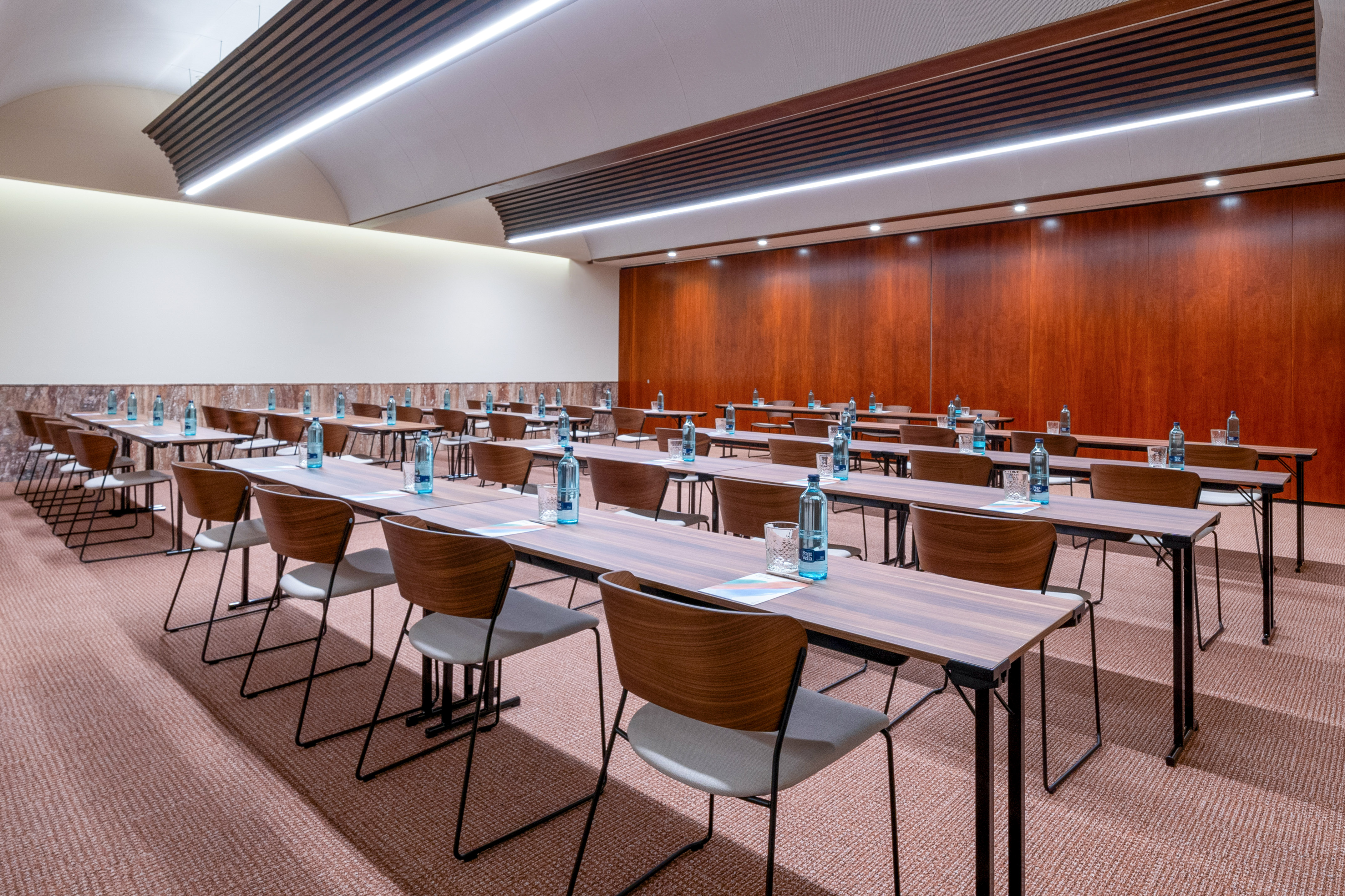 Modern training room setup with rows of tables, chairs, bottled water.