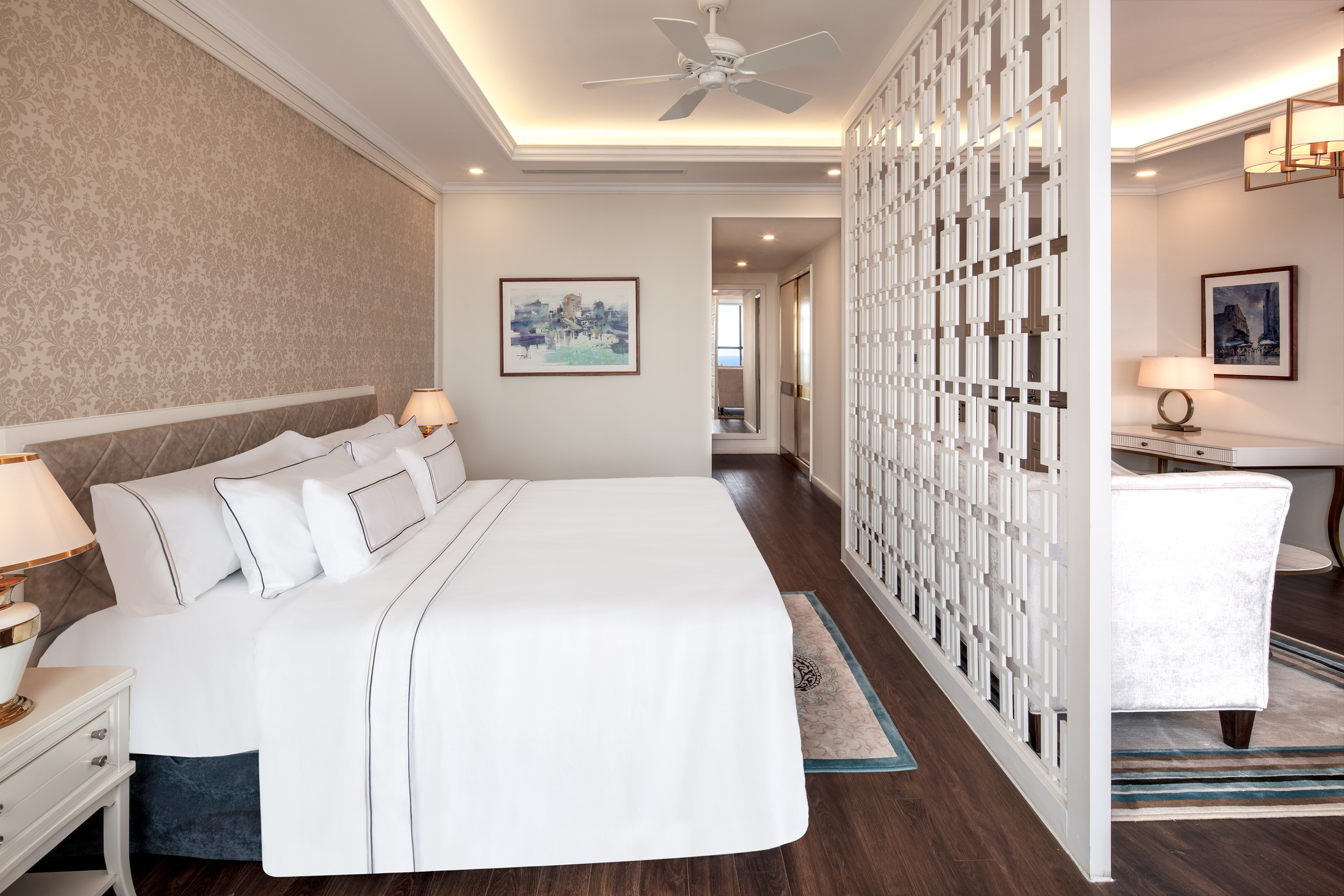 Luxury hotel bedroom with king bed, decorative screen, and modern lighting.