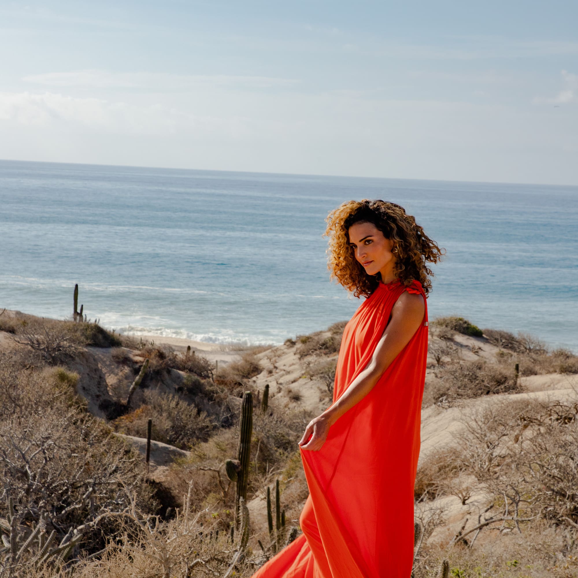 a woman in a red dress on a beach