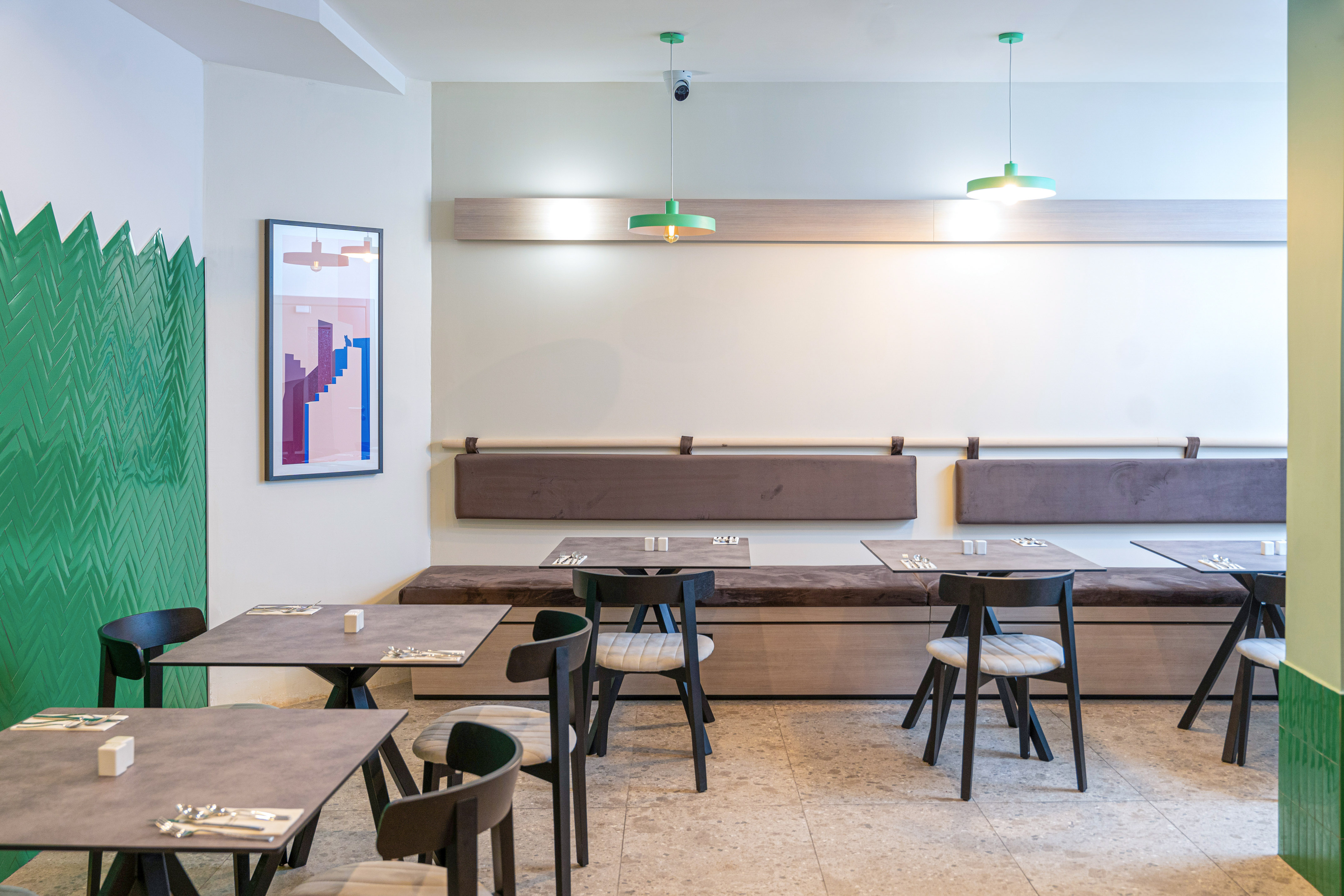 Chic restaurant dining area with green tiled wall, brown booths, and modern tables.