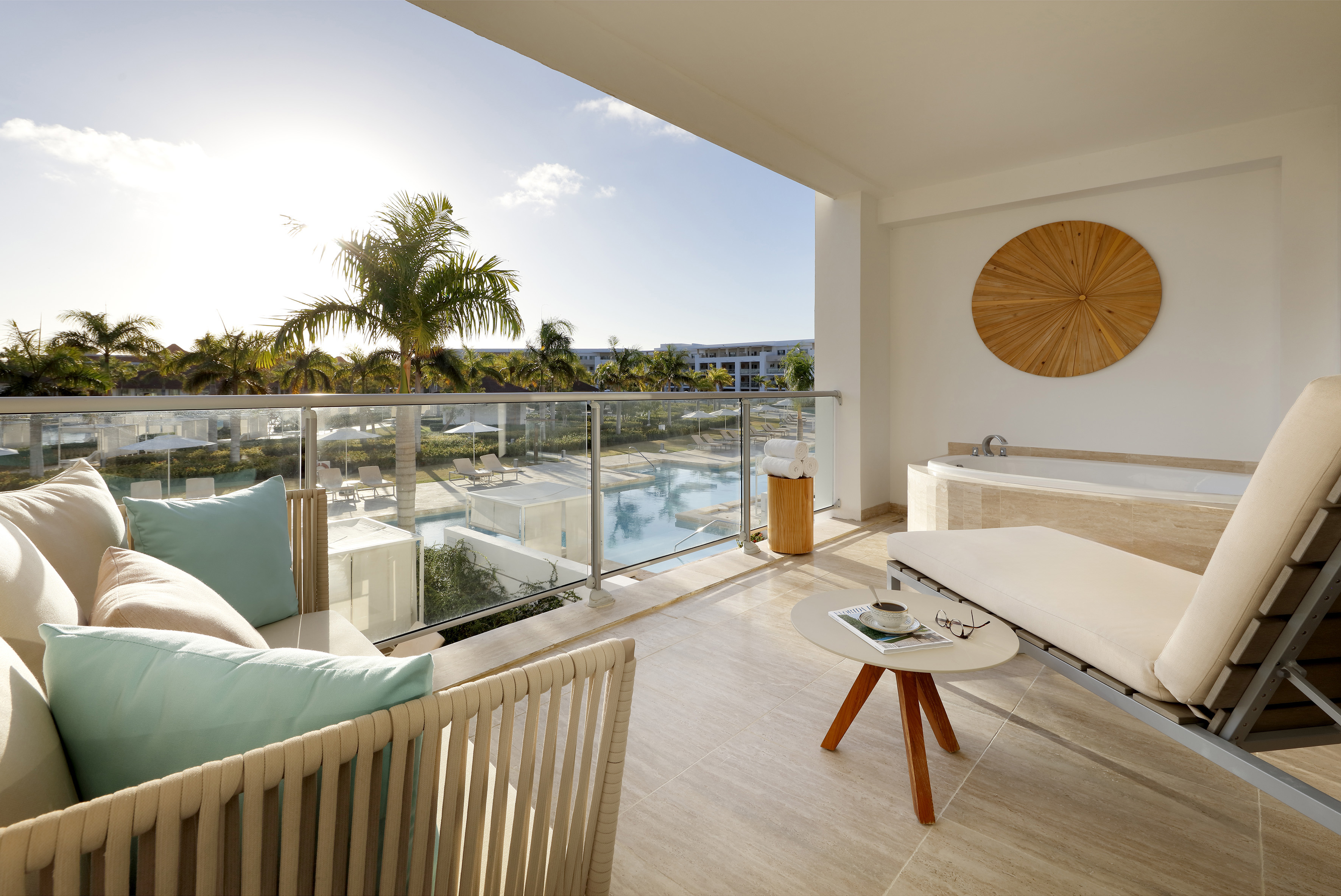 Tropical resort balcony with private hot tub, lounge, and pool view.