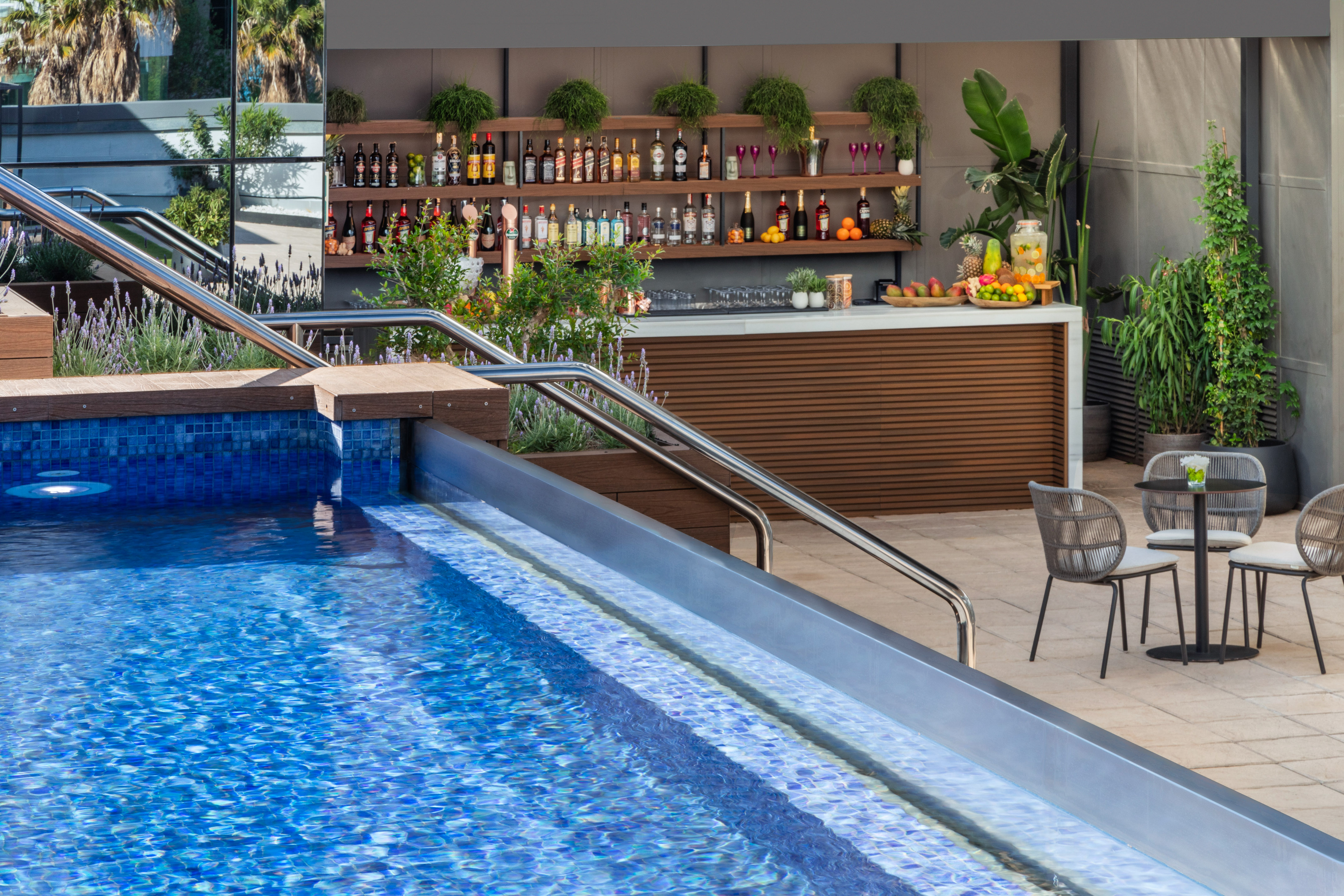 Hotel poolside bar and sparkling blue swimming pool with lounge area.