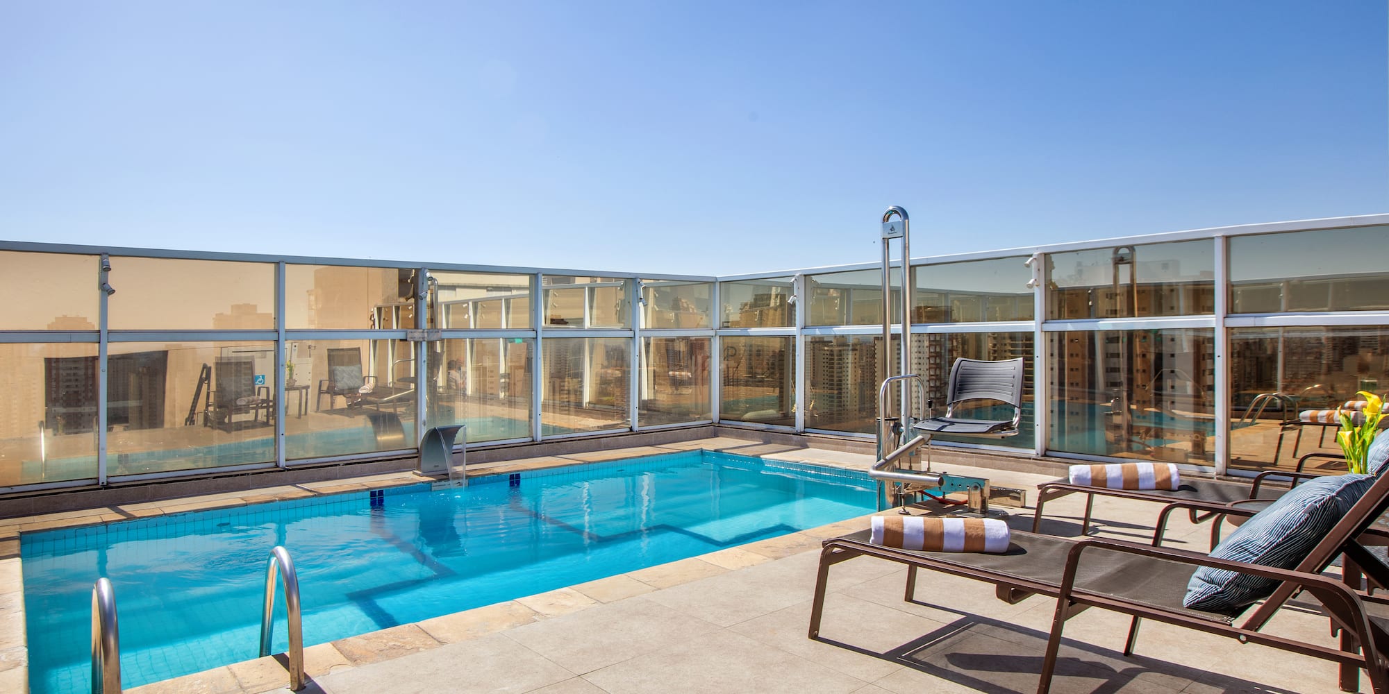 a pool with chairs and a deck chair on a rooftop