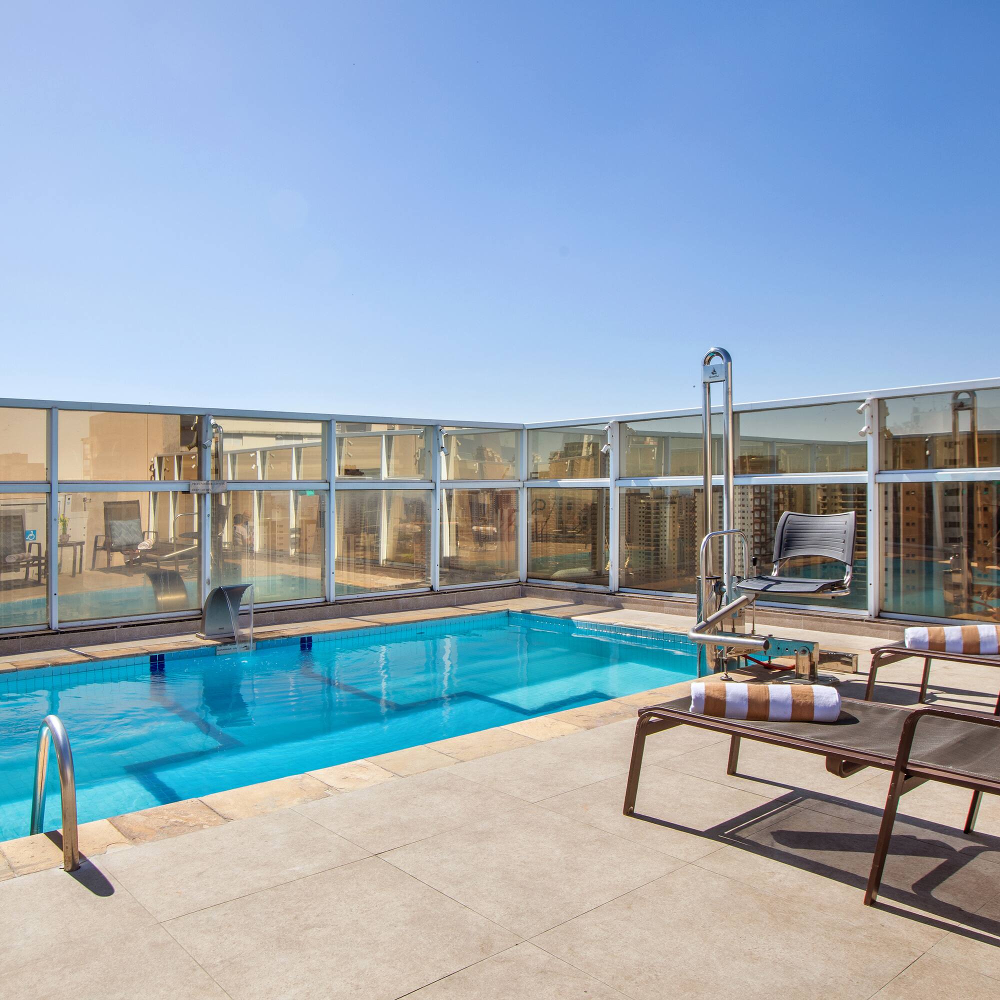a pool with chairs and a deck chair on a rooftop