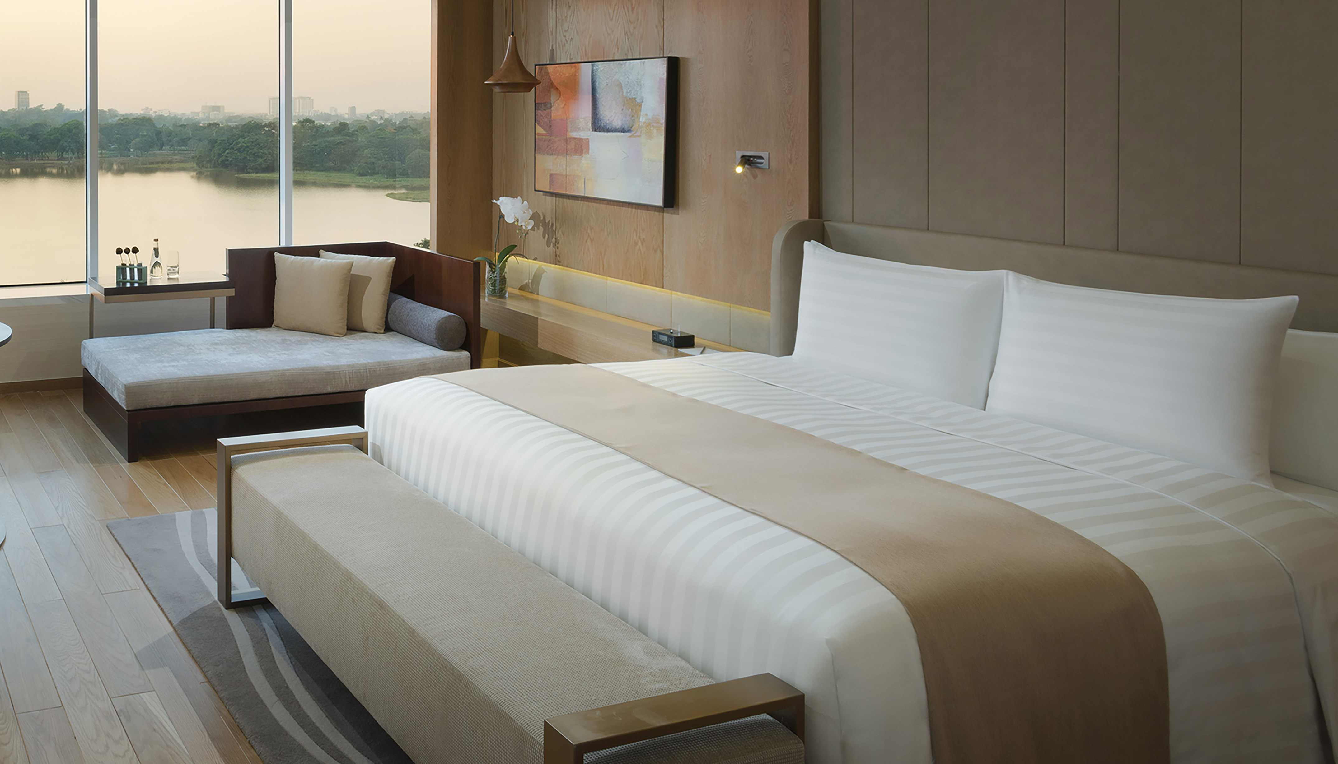 Luxury hotel bedroom with king bed, daybed, lake view, and modern decor.