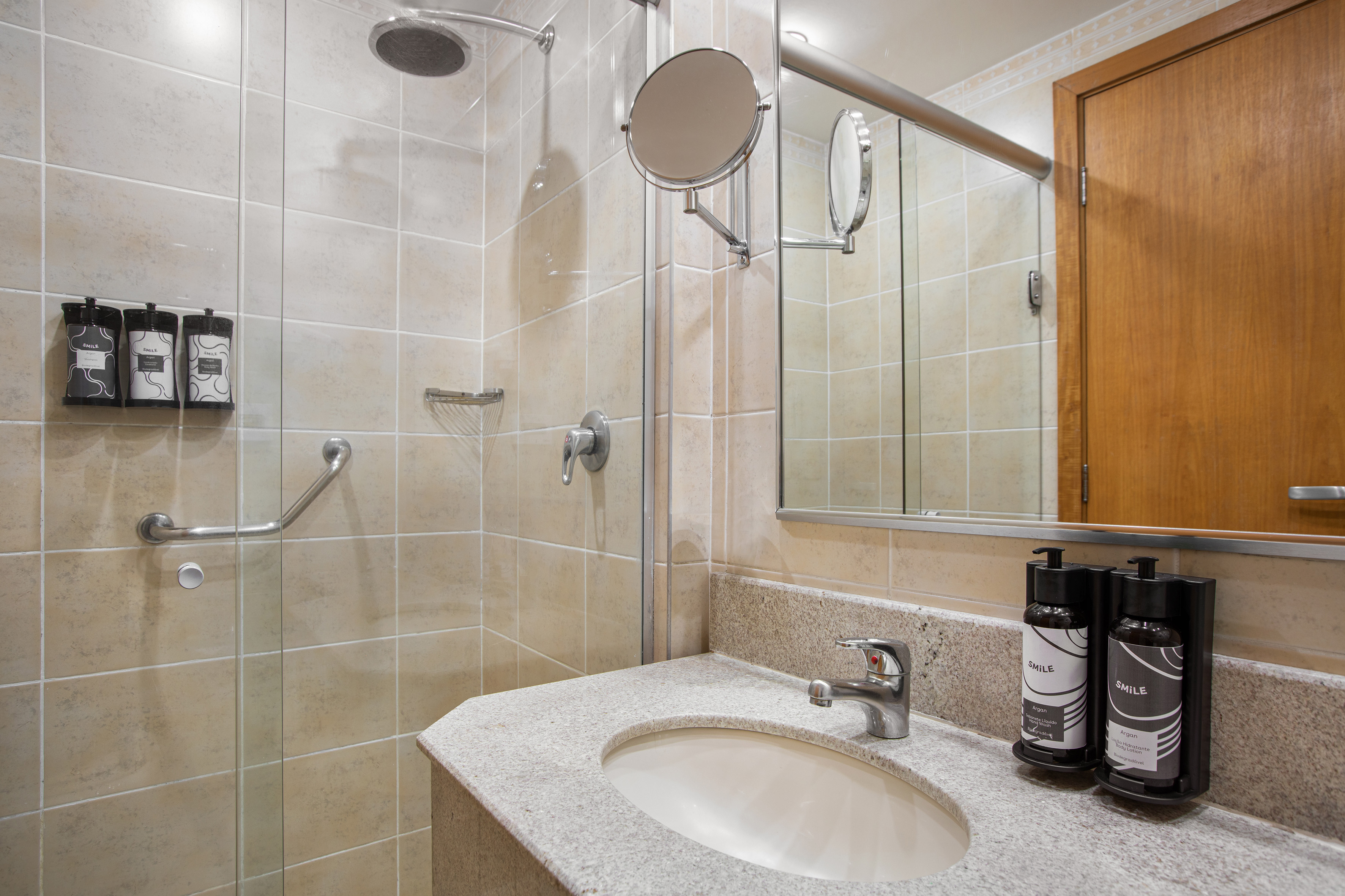 Modern tiled bathroom with shower, grab bar, granite sink, and amenities.