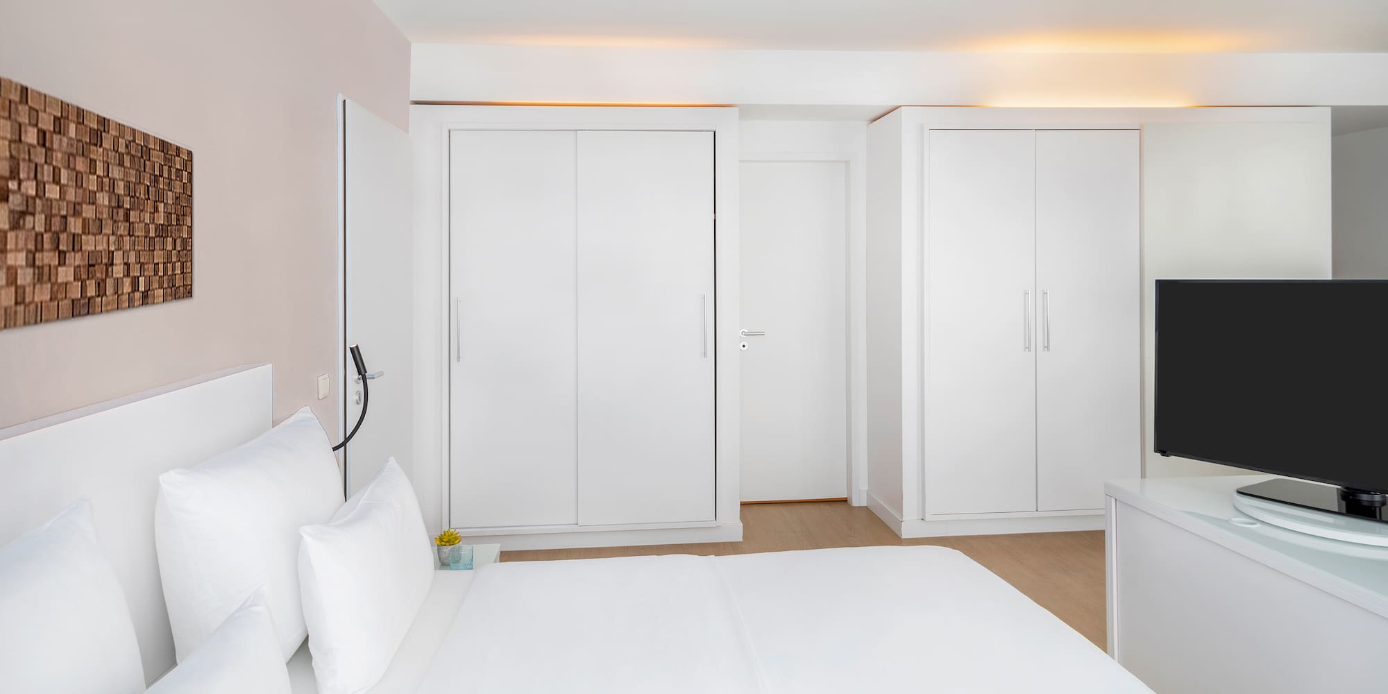 a bedroom with white furniture and a tv