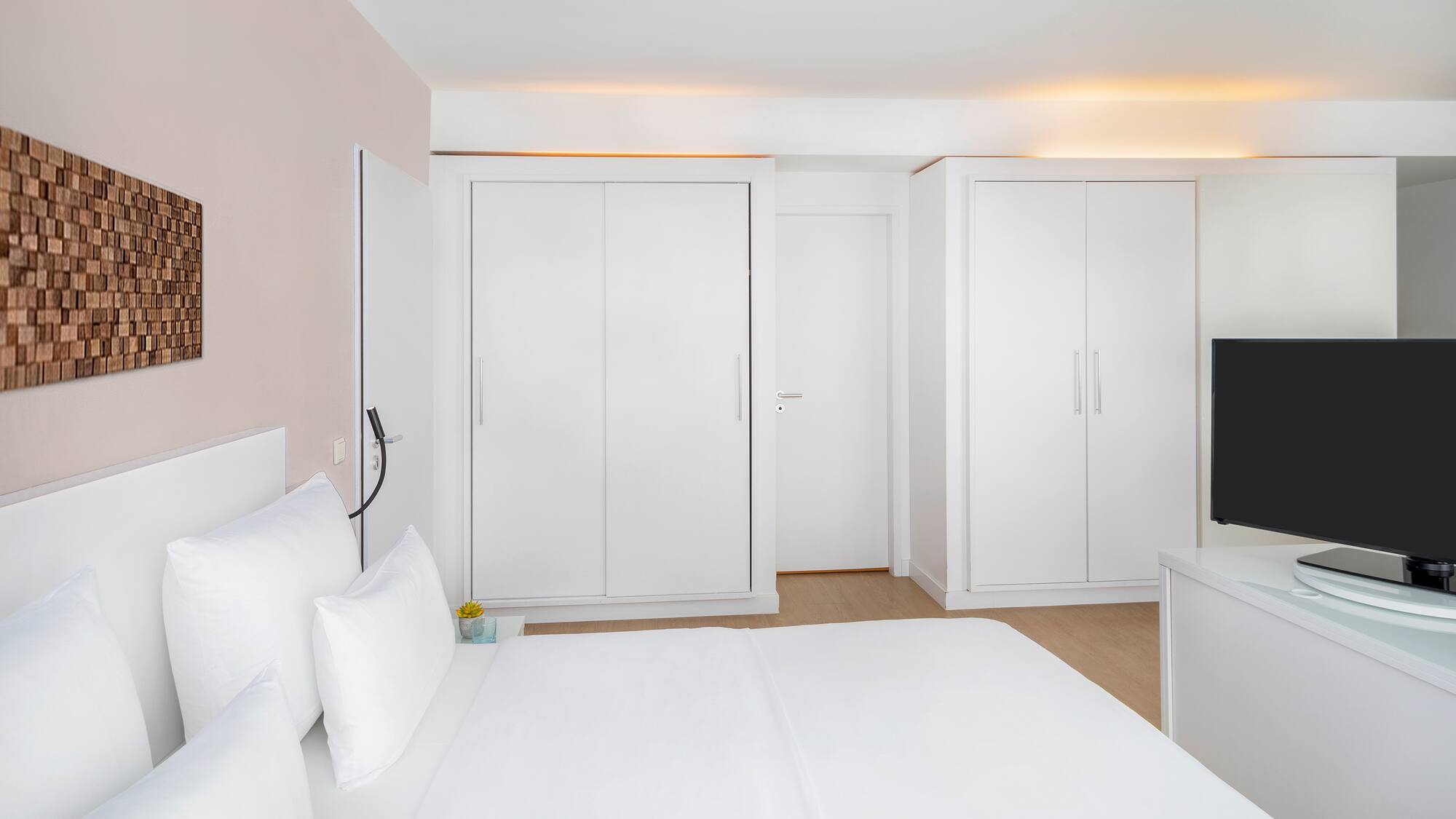 a bedroom with white furniture and a tv