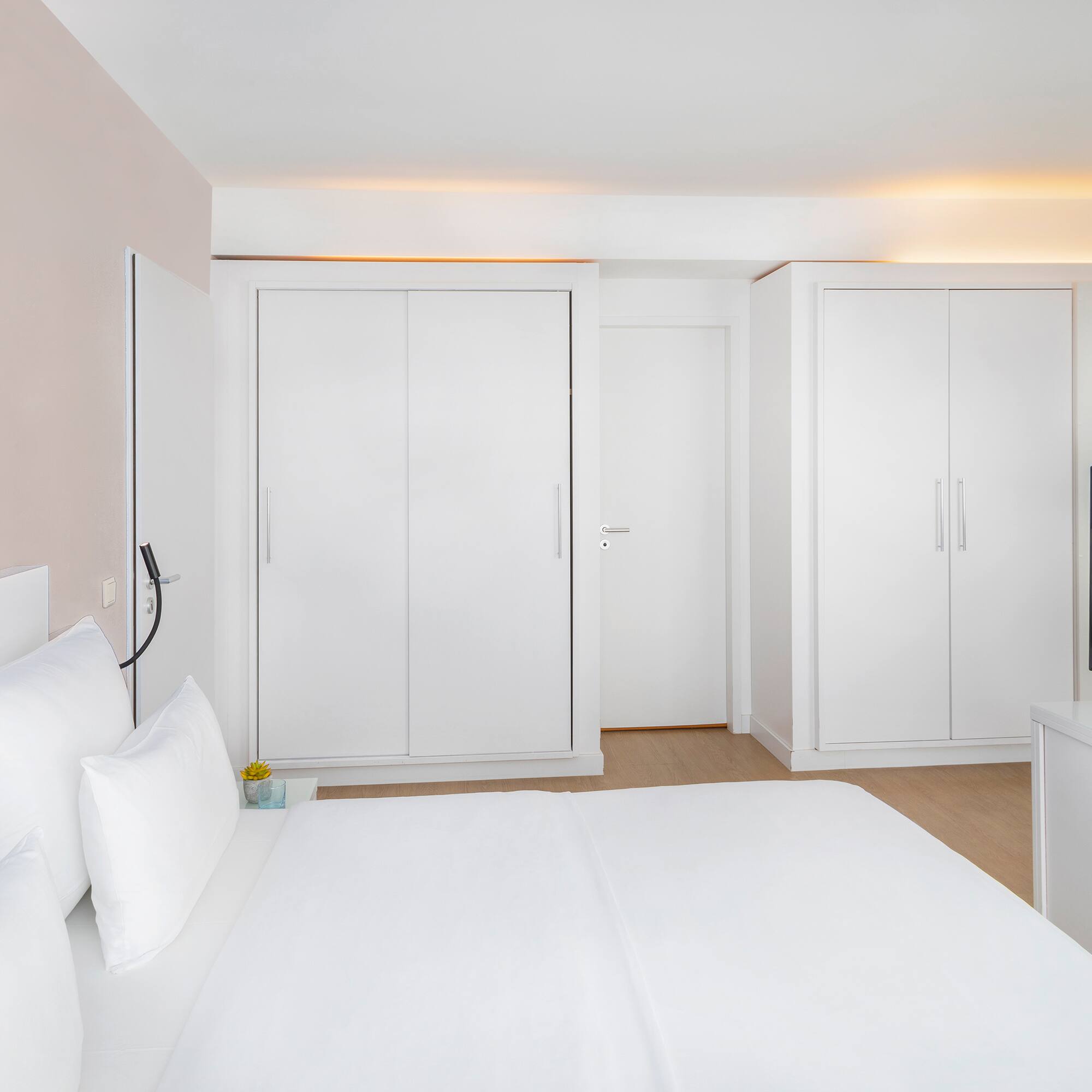 a bedroom with white furniture and a tv