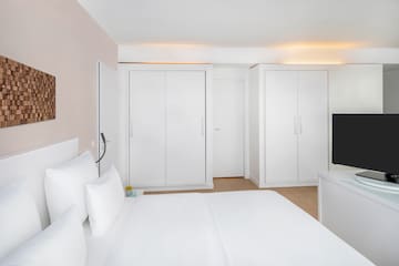 a bedroom with white furniture and a tv