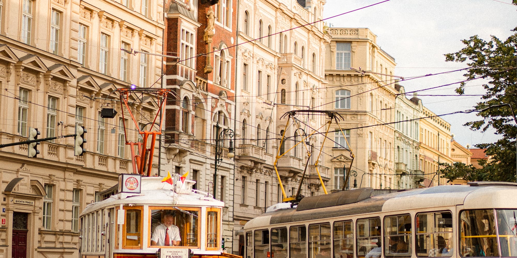 a red and white trolleys on a street with buildings in the background
