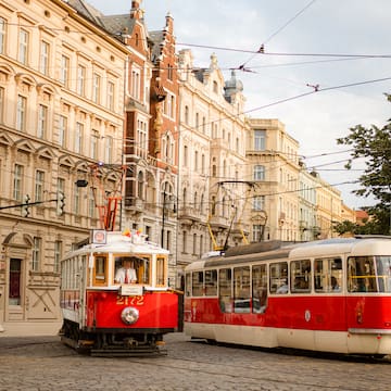 a red and white trolleys on a street with buildings in the background