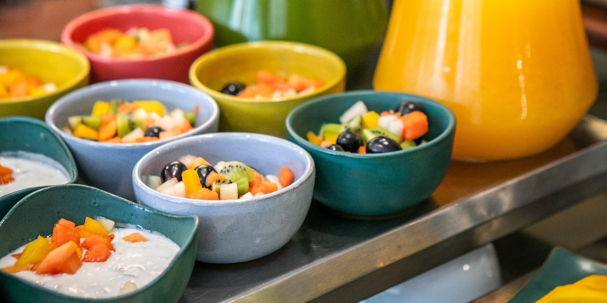 Colorful fresh fruit salad, yogurt, green and orange juice, kiwi, papaya.