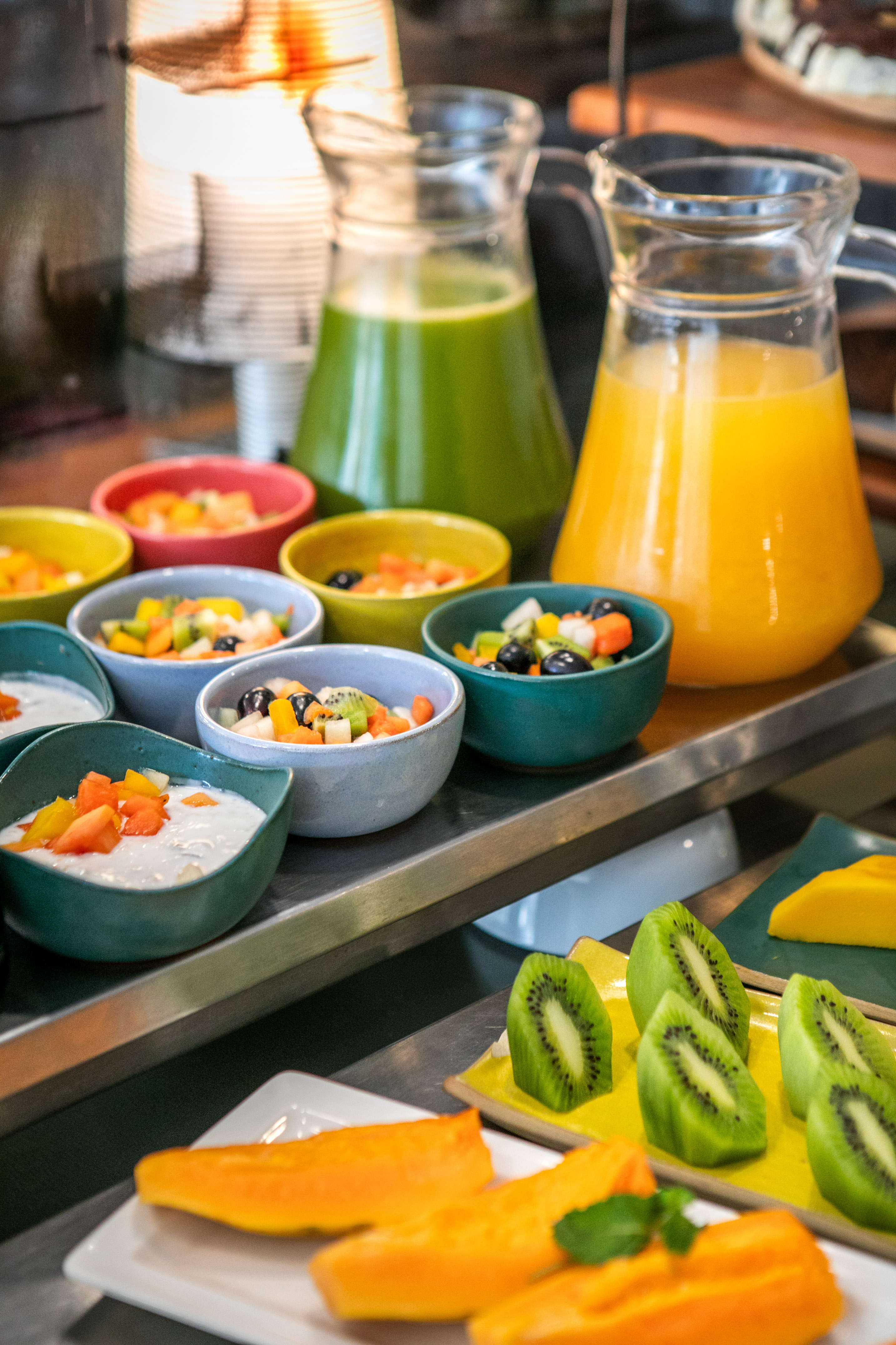 Colorful fresh fruit salad, yogurt, green and orange juice, kiwi, papaya.