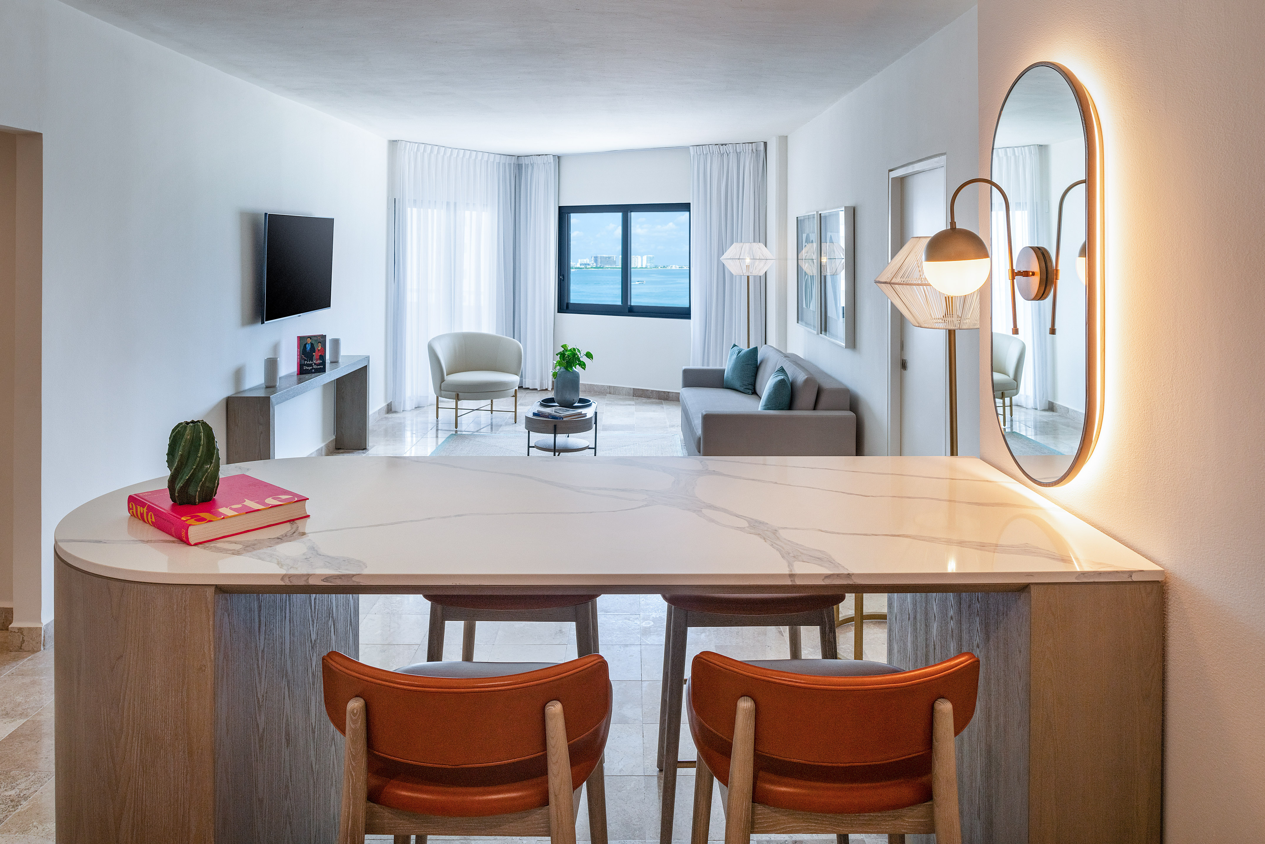 Modern apartment living room with ocean view, kitchen island and bar stools.