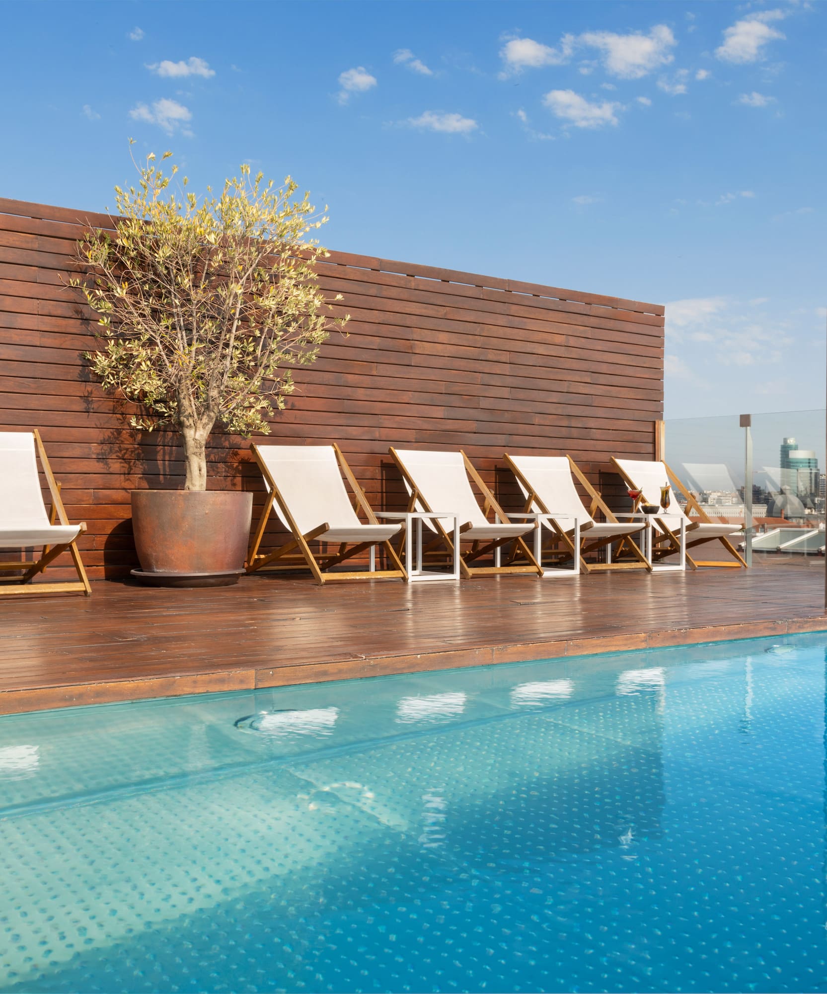 a pool with chairs and a tree on the side