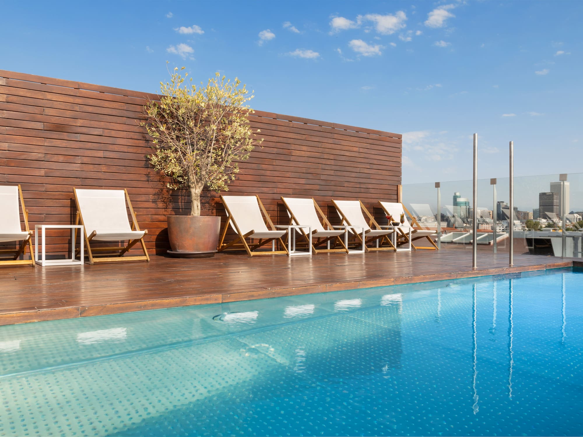 a pool with chairs and a tree on the side