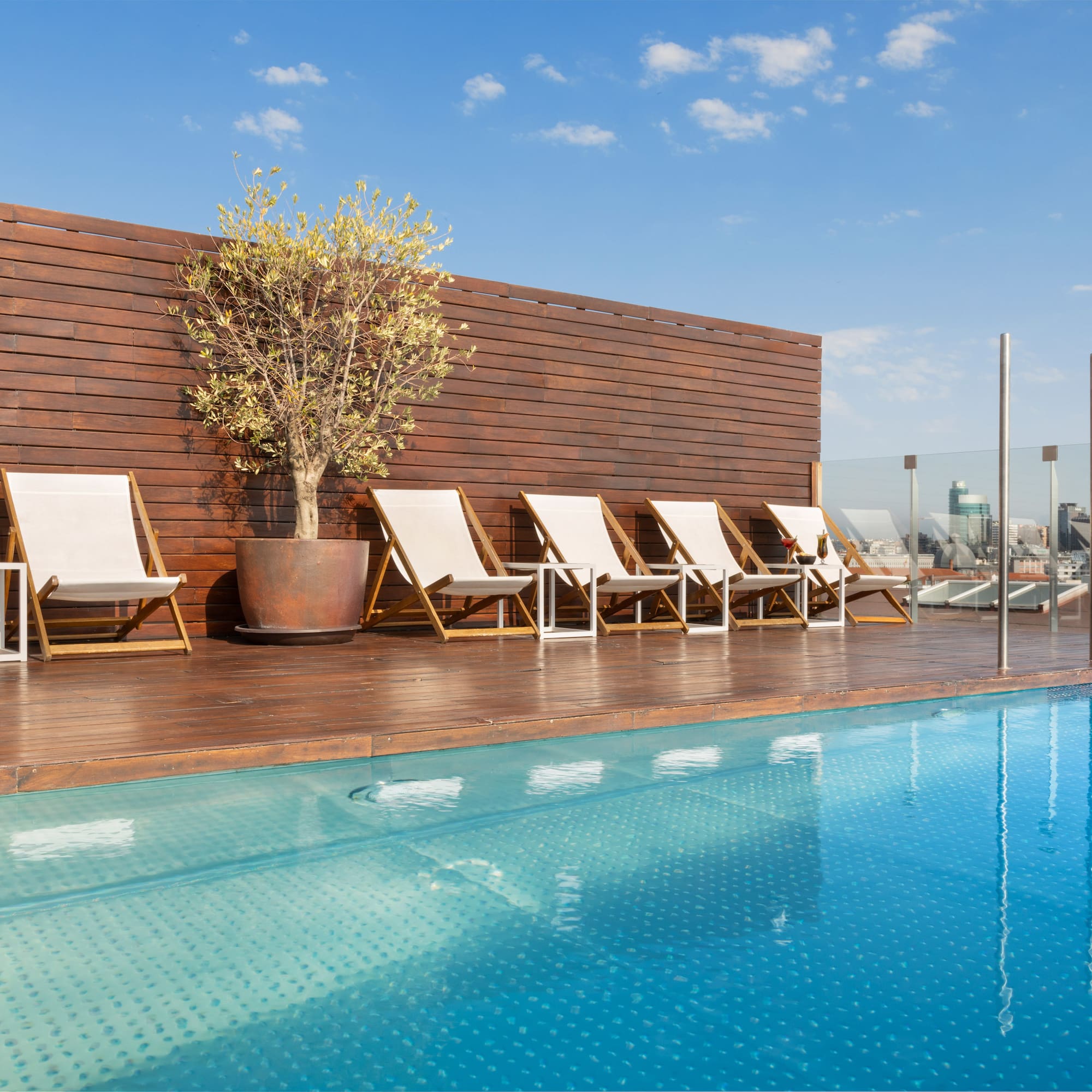 a pool with chairs and a tree on the side