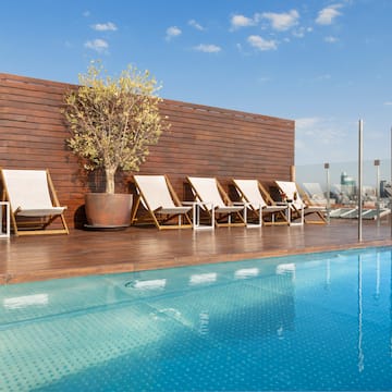 a pool with chairs and a tree on the side