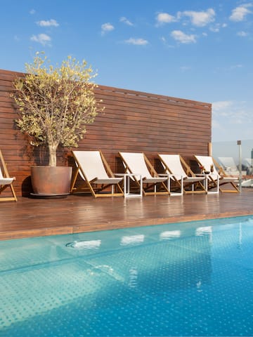 a pool with chairs and a tree on the side