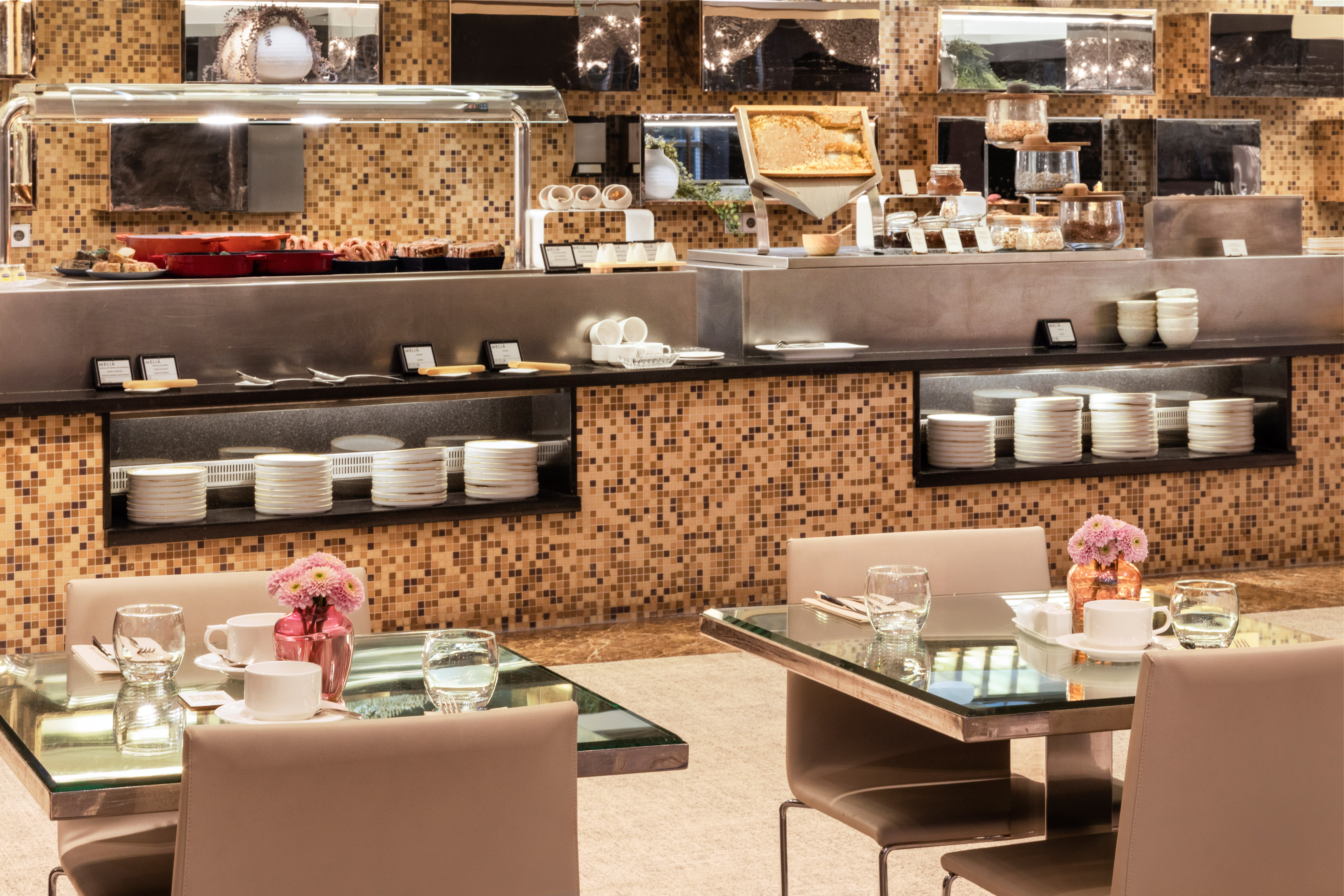 Hotel breakfast buffet featuring hot dishes, pastries, honey, and elegant dining tables.