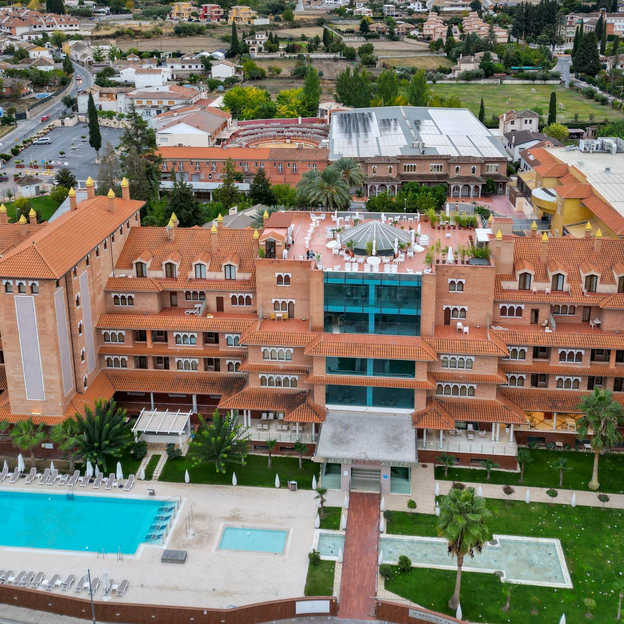 Aerial view: Granada hotel with red tiled roofs, swimming pool, and gardens.