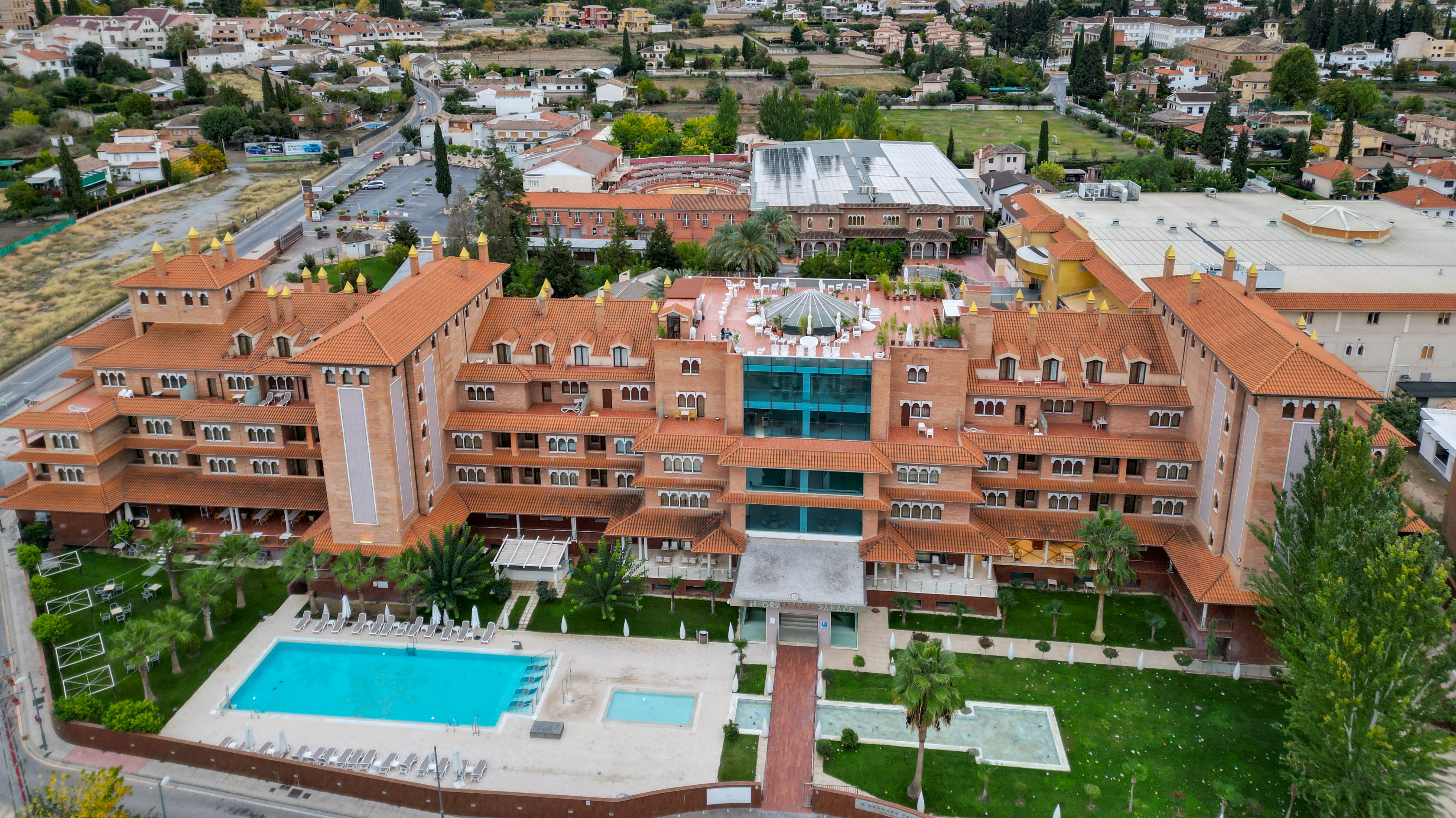 El Granada Palace luxury hotel, aerial view of red tile roof, pools, and city.