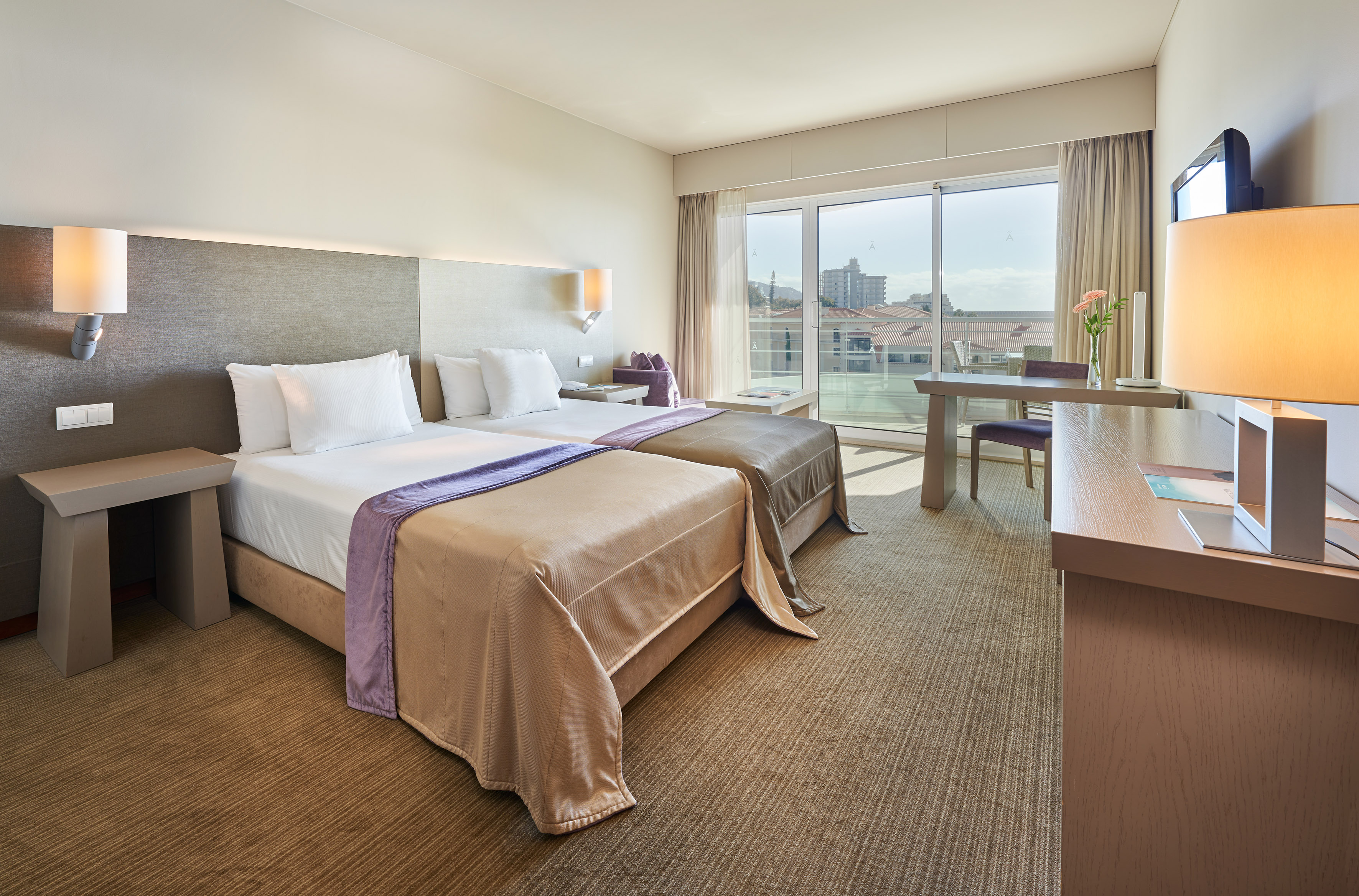 Modern hotel twin room with balcony and city view.