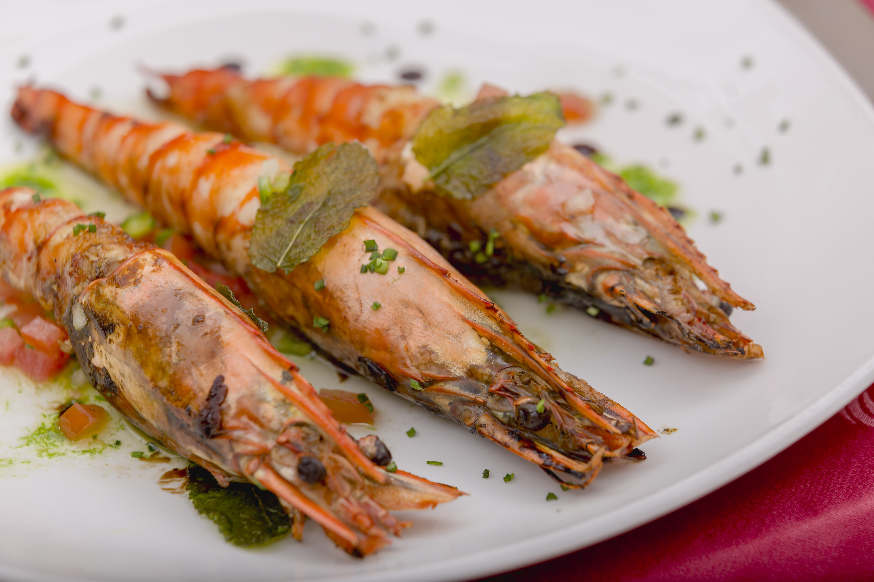 Grilled giant prawns with mint and chives, gourmet seafood dish.
