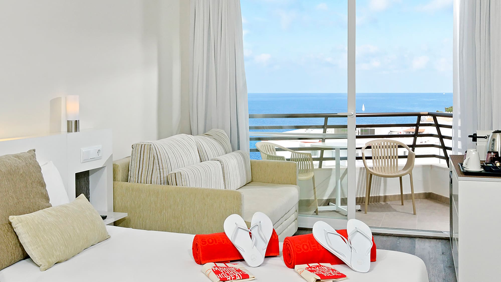 a room with a bed and a balcony overlooking the ocean