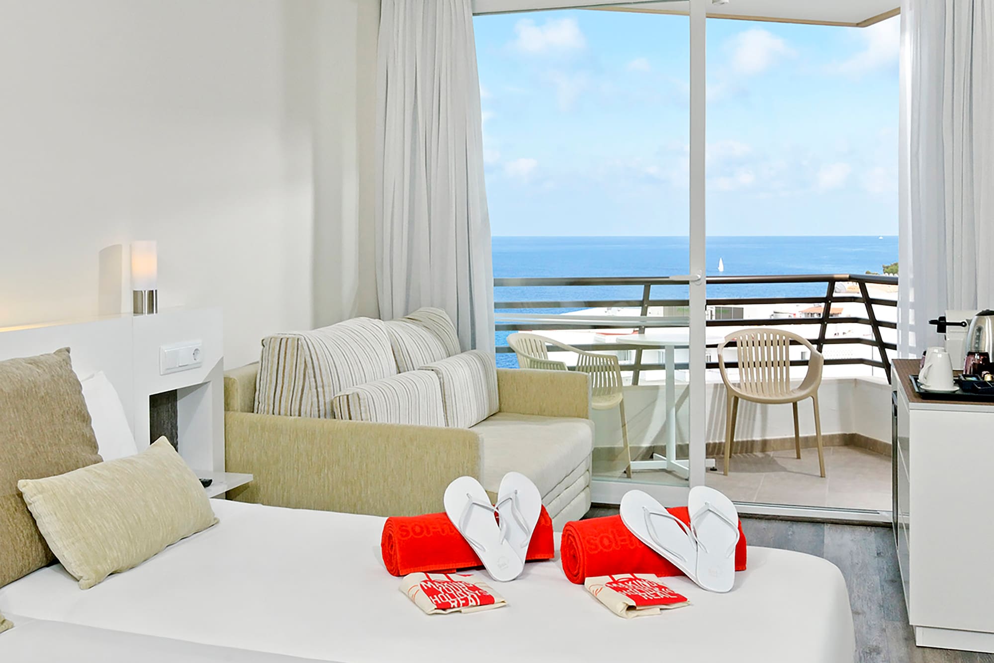 a room with a bed and a balcony overlooking the ocean