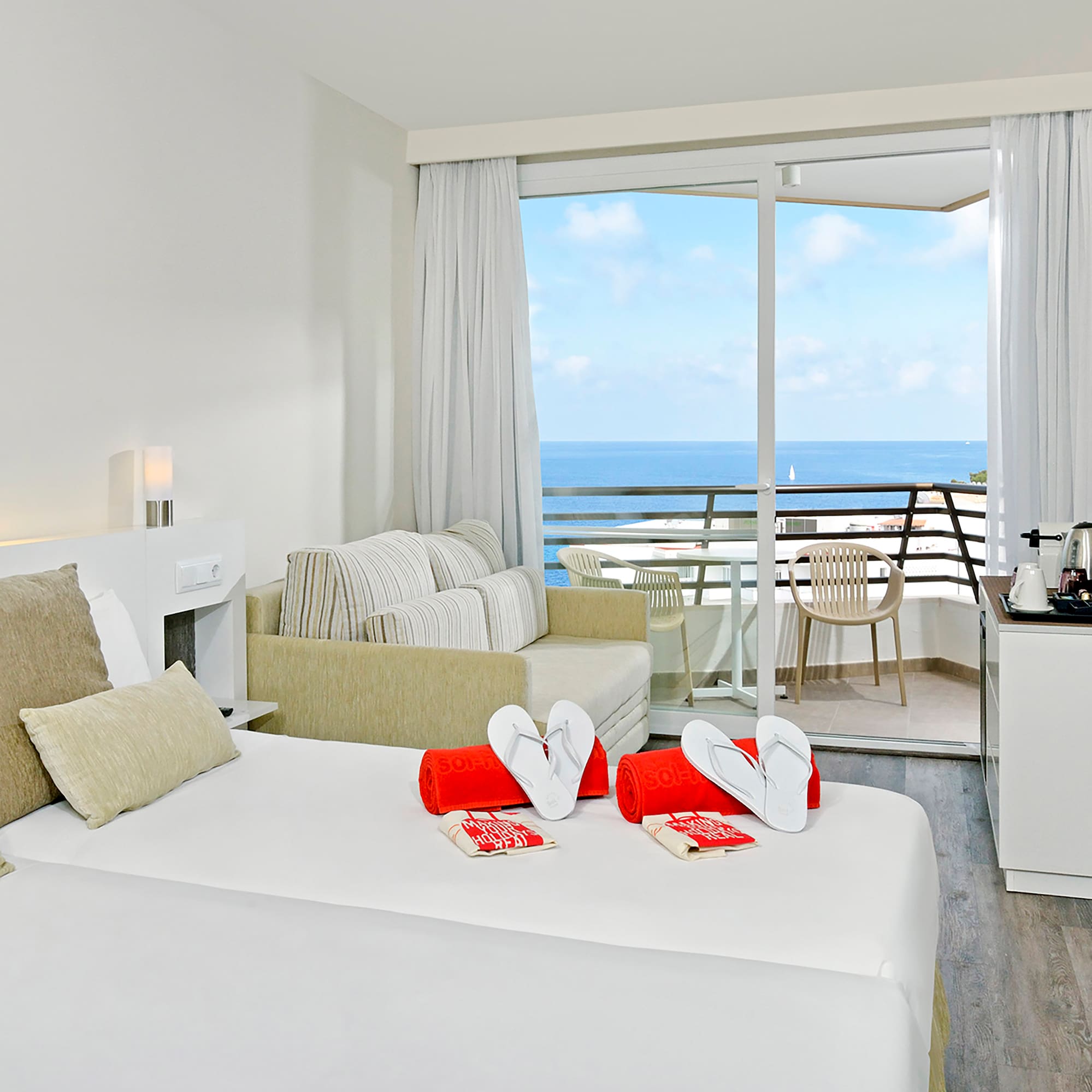 a room with a bed and a balcony overlooking the ocean