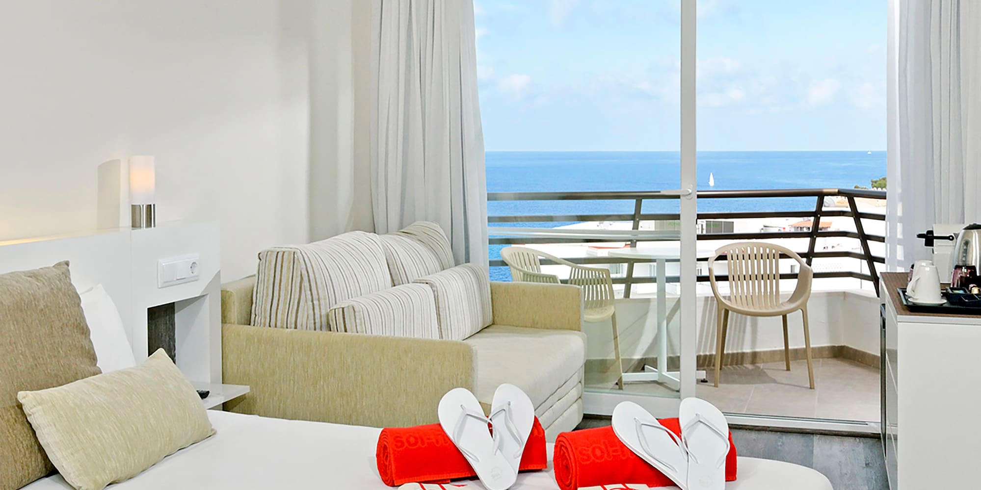 a room with a bed and a balcony overlooking the ocean