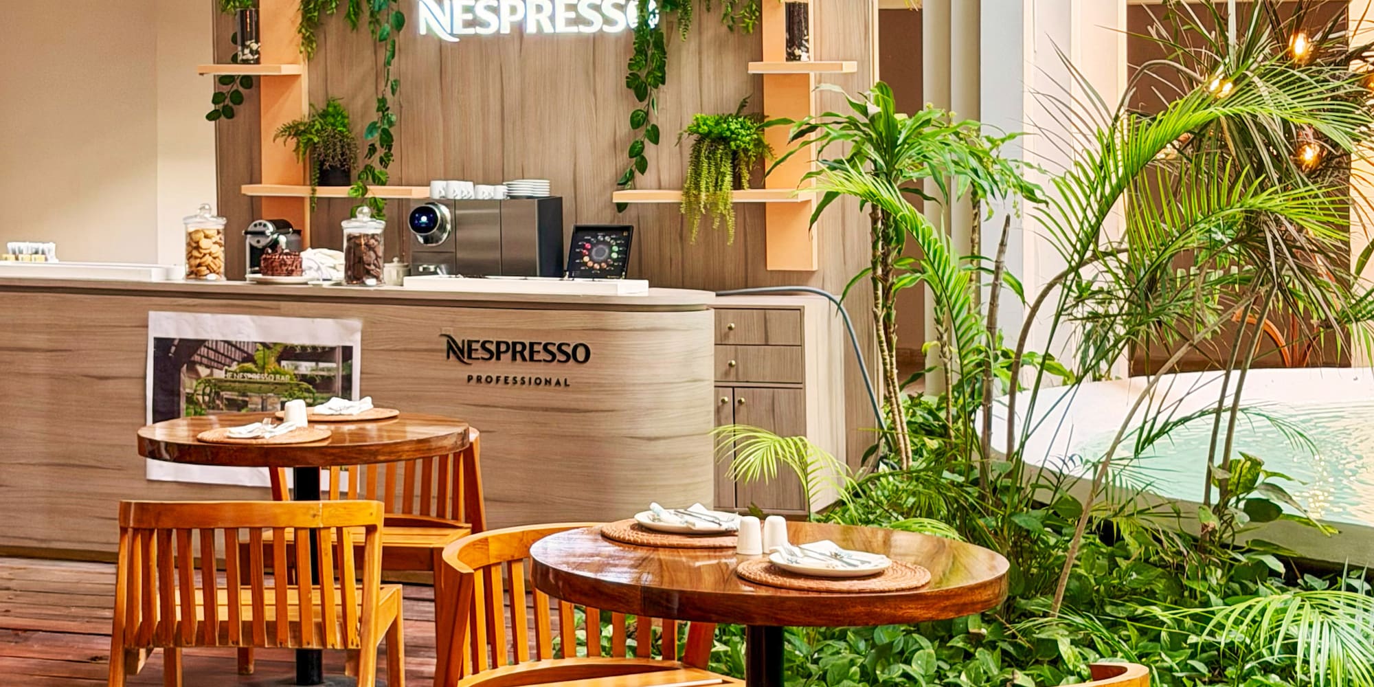 Nespresso Professional cafe with wooden seating and lush greenery.