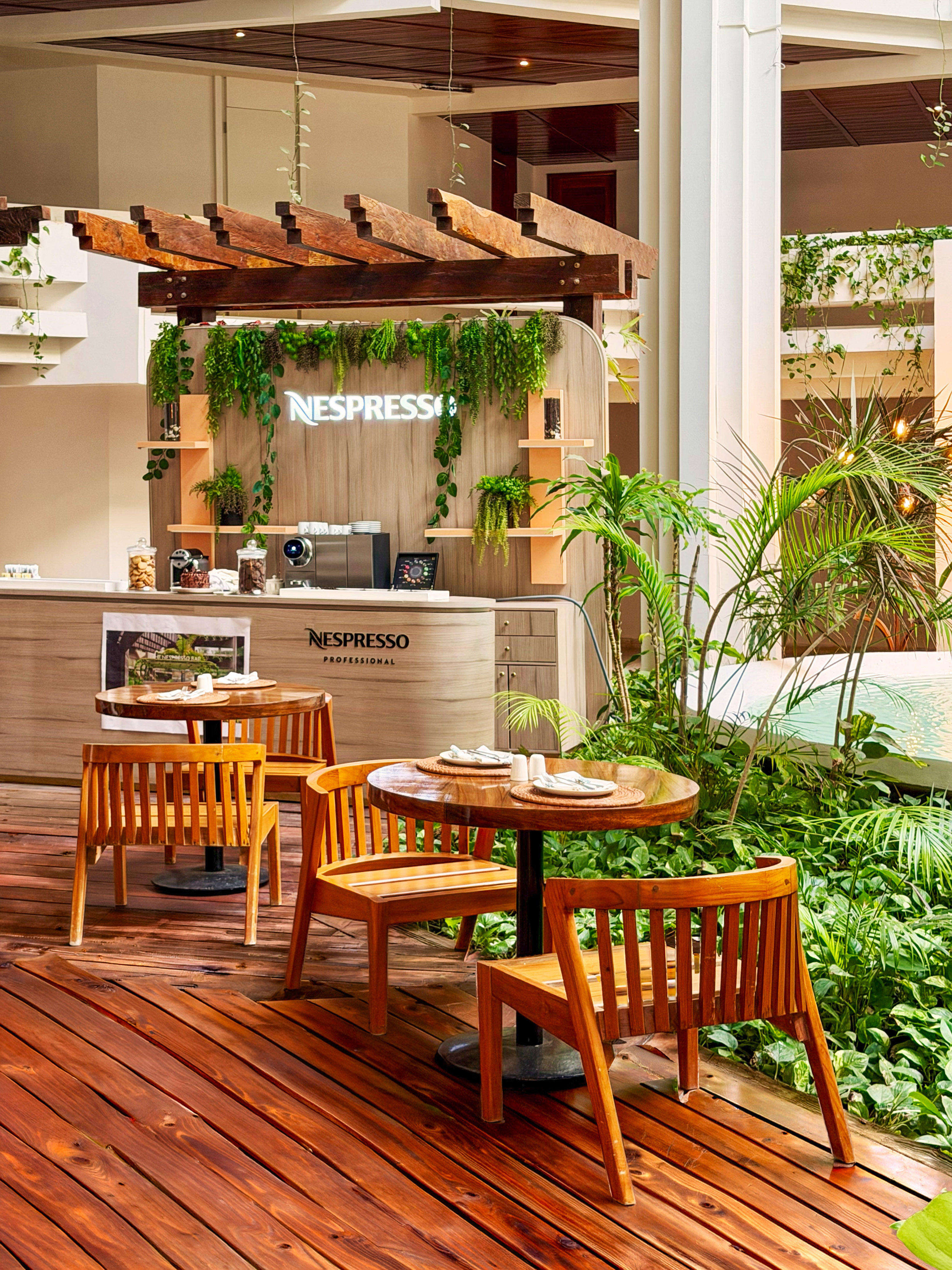 Nespresso Professional cafe with wooden seating and lush greenery.