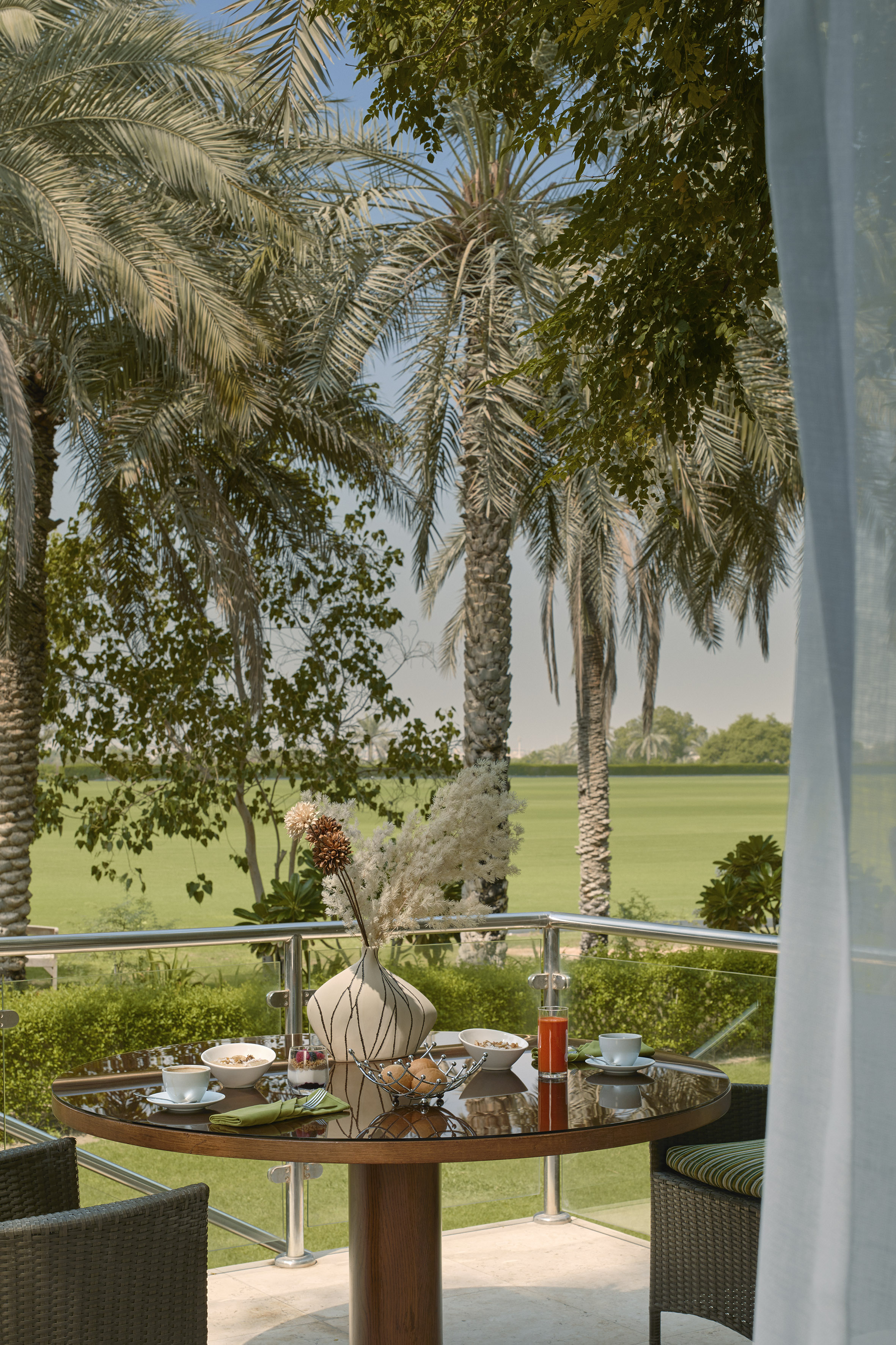 Balcony breakfast overlooking a lush golf course with palm trees.