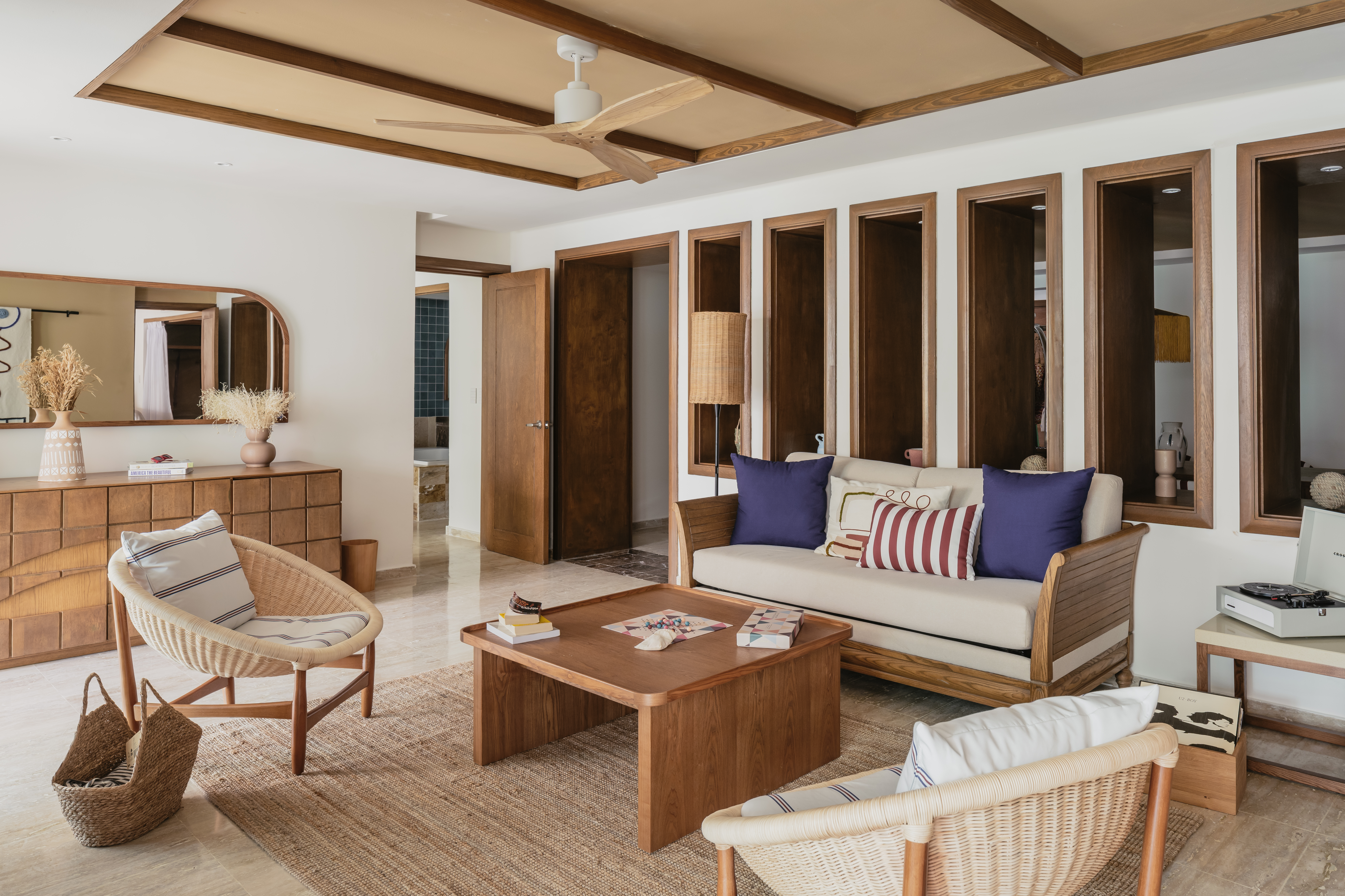 Modern living room with wood furniture, wicker chairs, and neutral decor.