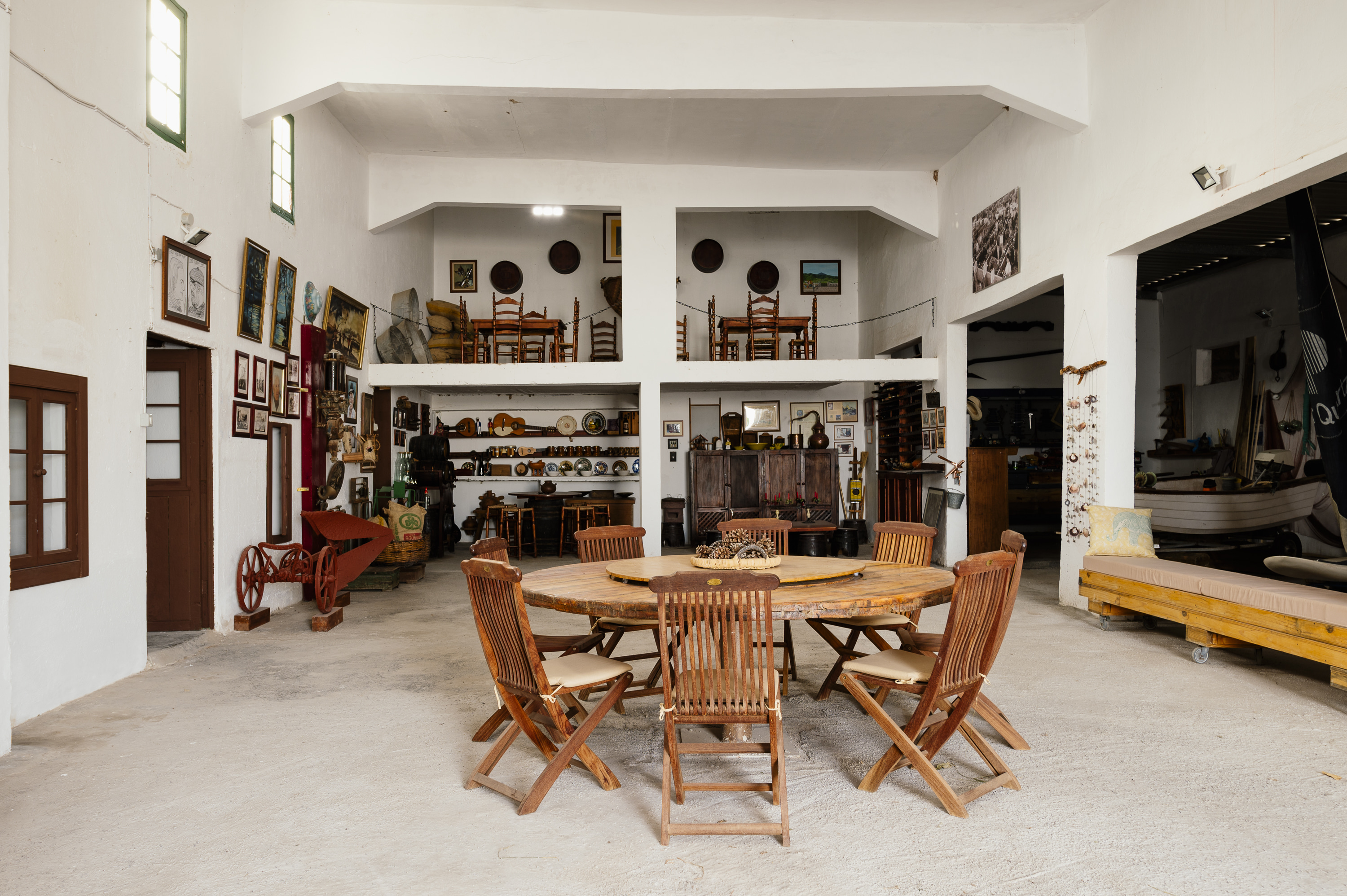 Rustic hall with large wooden table, traditional style, and antique displays.