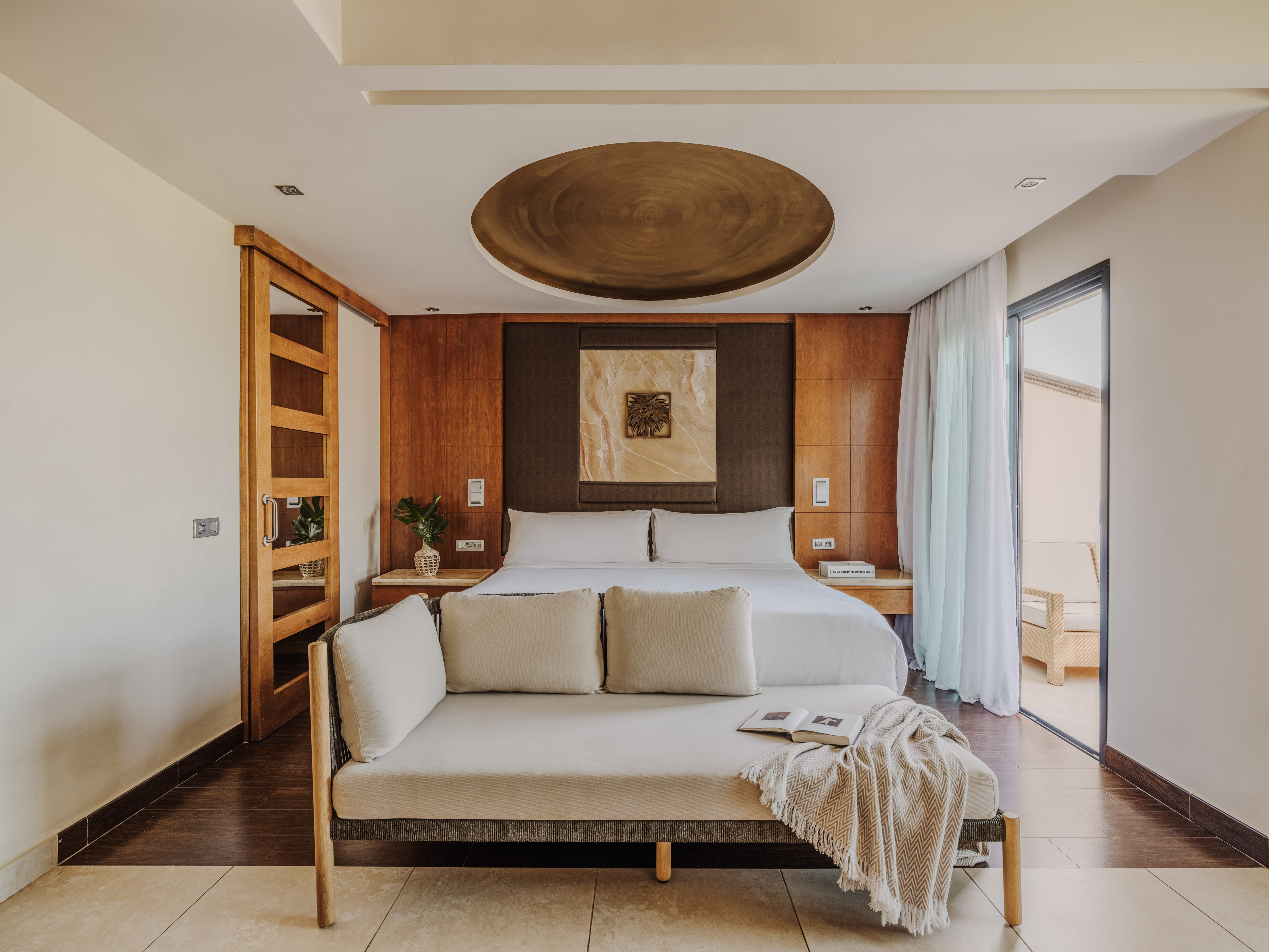 Luxurious hotel bedroom with king bed, modern wood accents, and daybed.