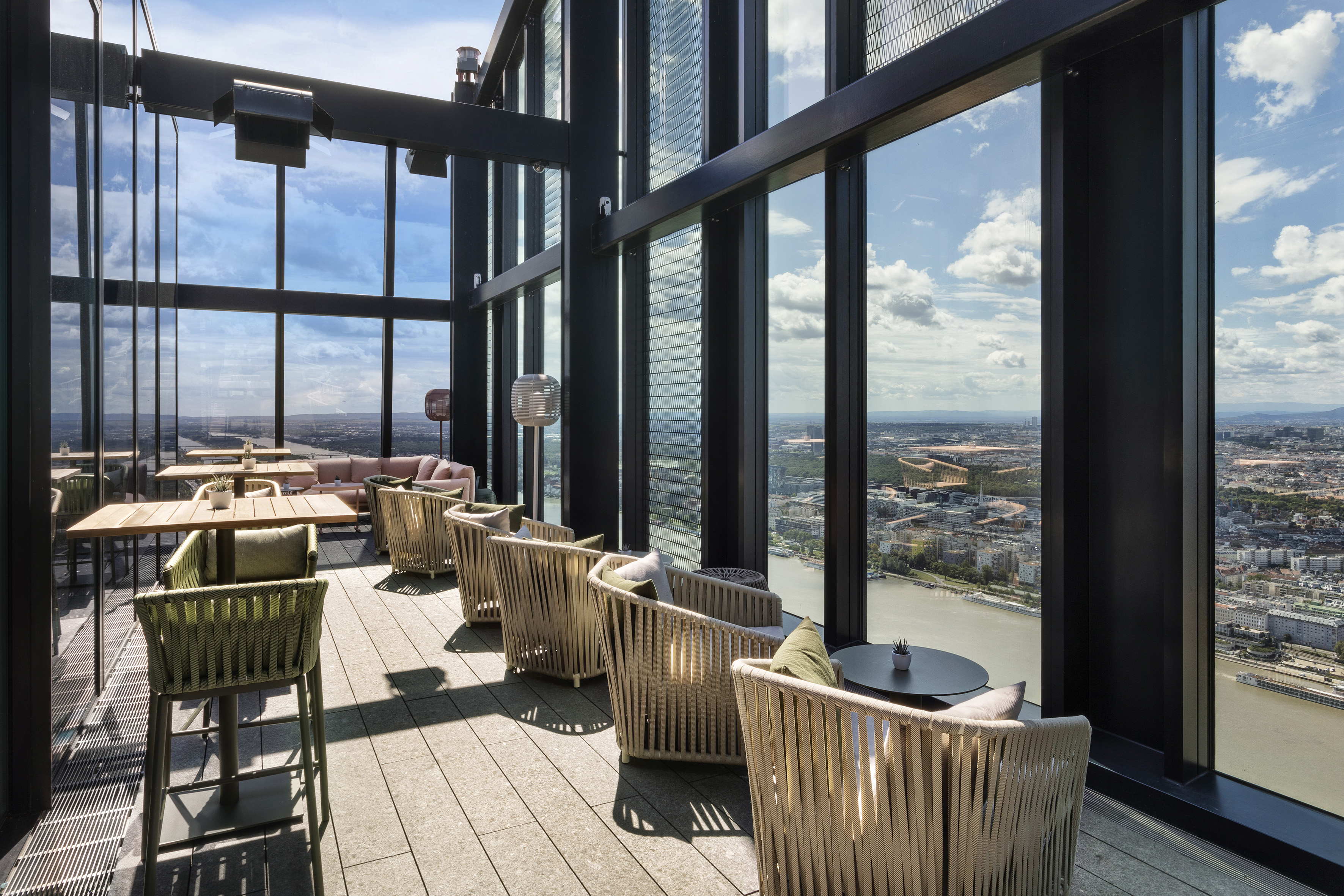 Modern high-rise rooftop bar with panoramic city and river views.
