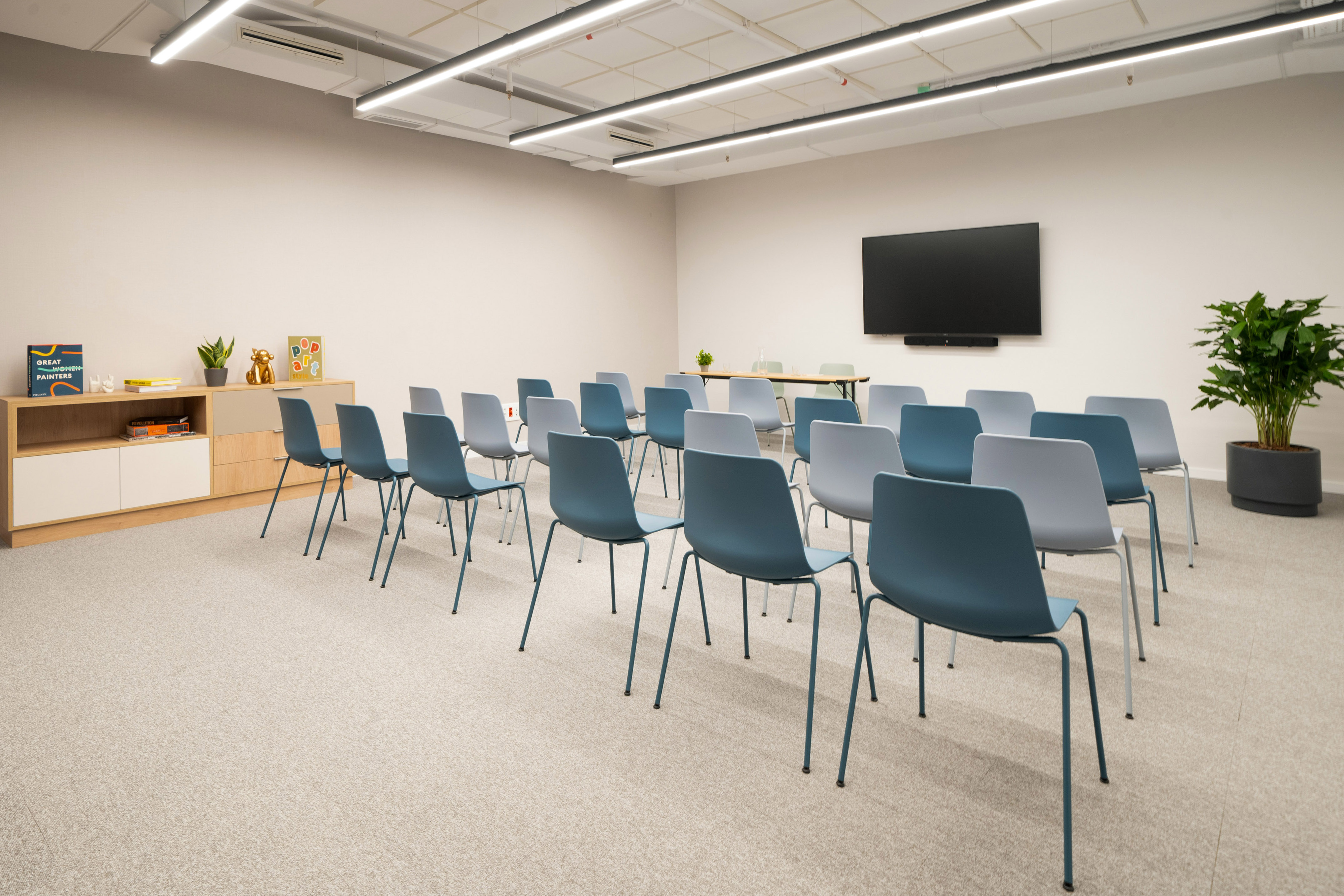 Modern meeting room with blue chairs and large screen for presentations.