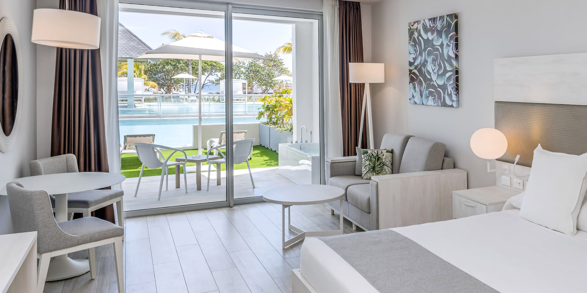 a bedroom with a bed and chairs and a pool in the background