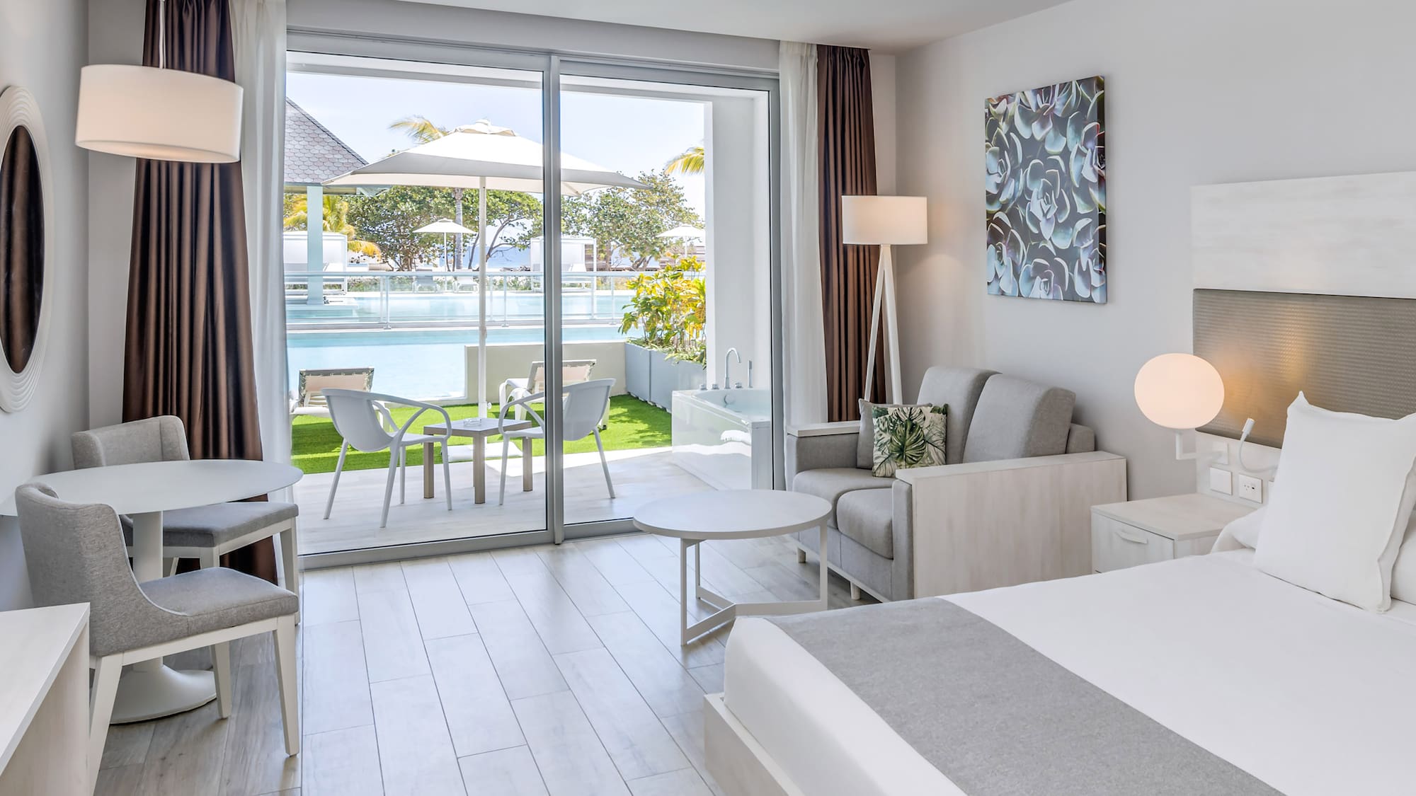 a bedroom with a bed and chairs and a pool in the background