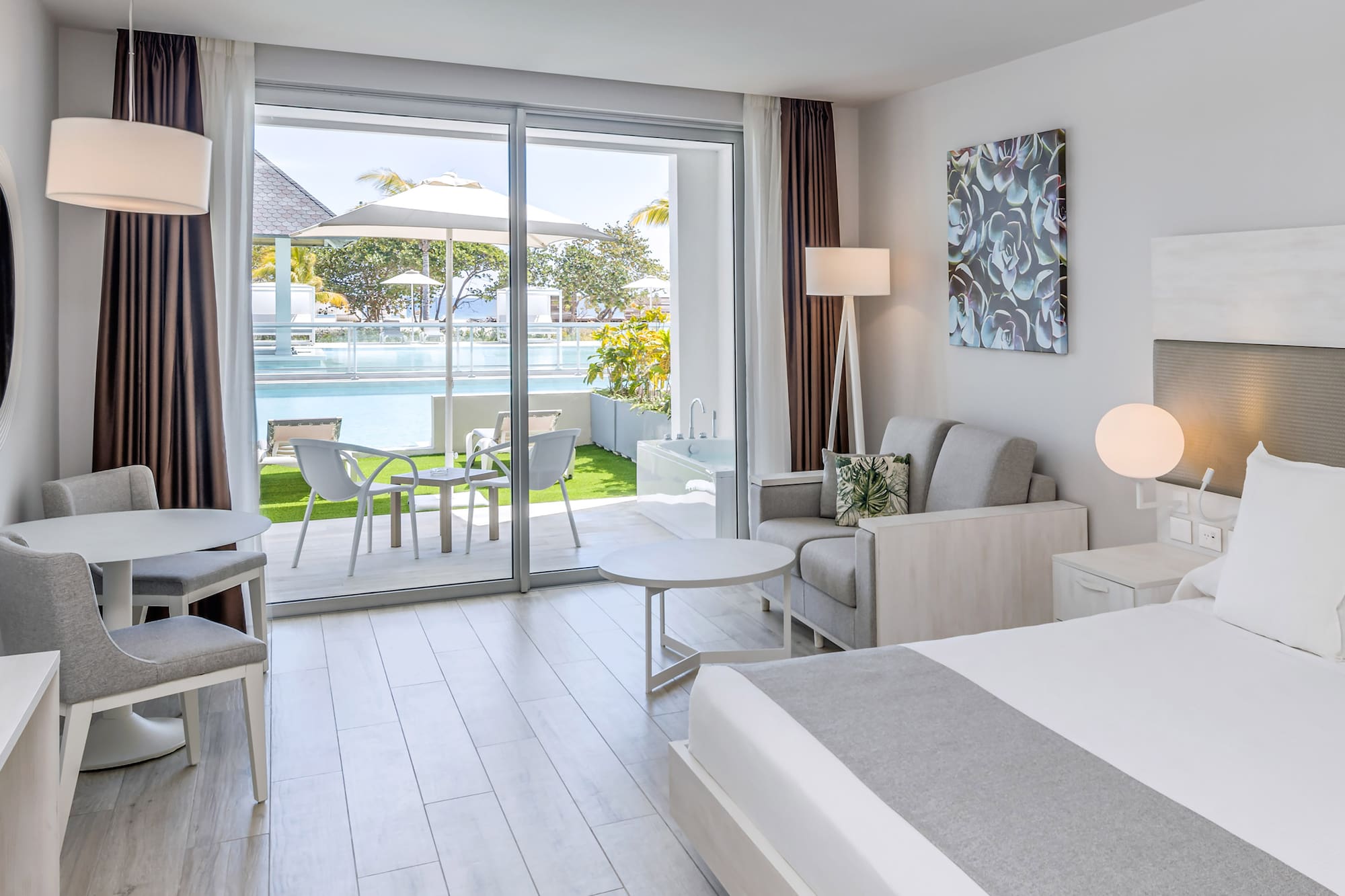 a bedroom with a bed and chairs and a pool in the background