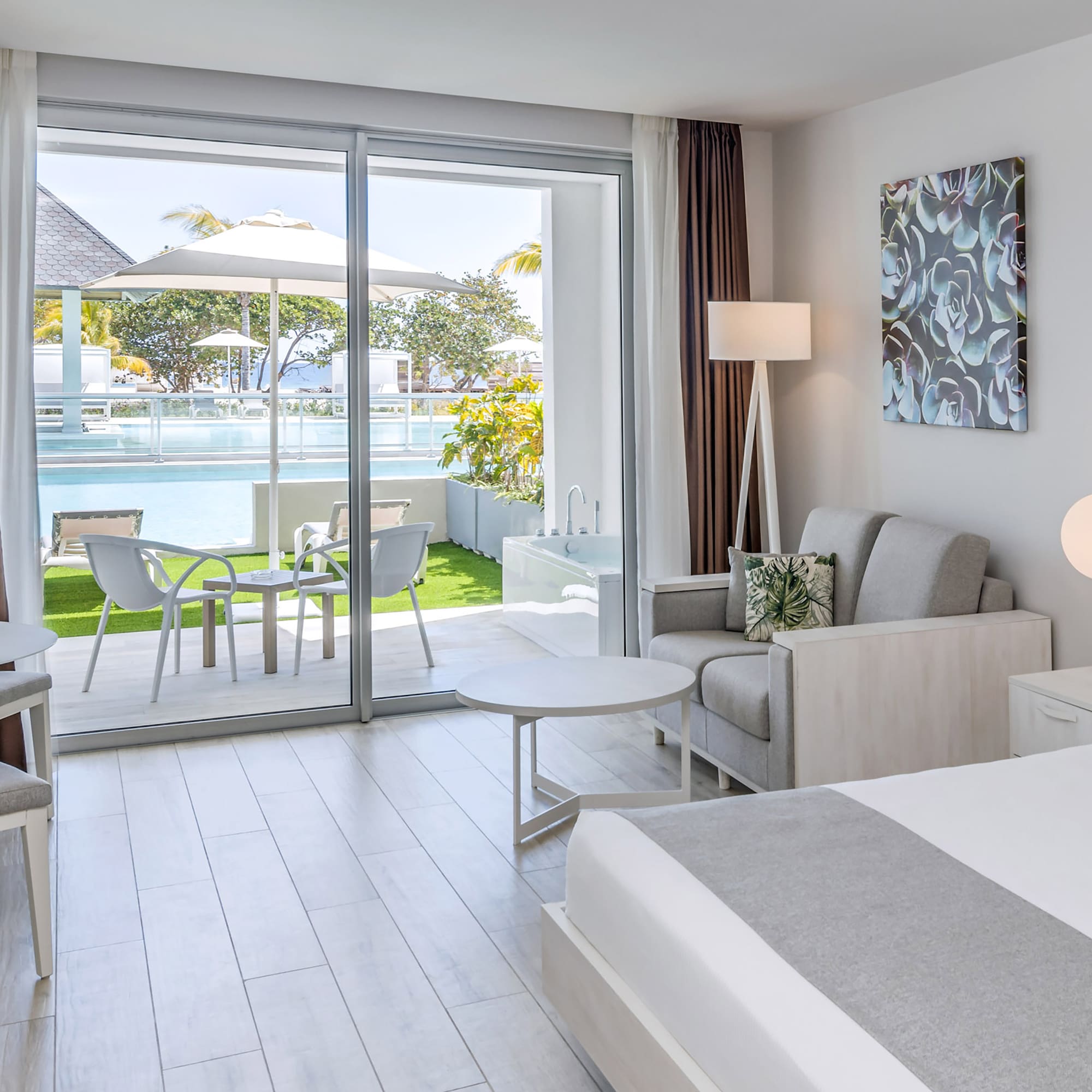 a bedroom with a bed and chairs and a pool in the background
