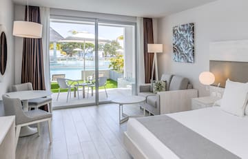 a bedroom with a bed and chairs and a pool in the background