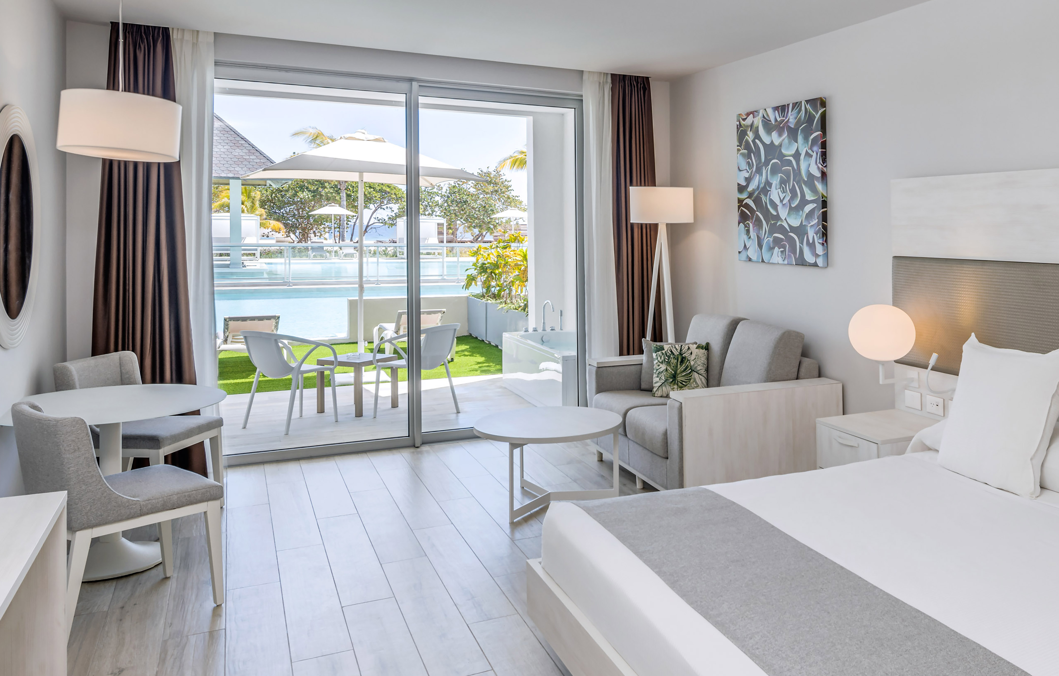 a bedroom with a bed and chairs and a pool in the background